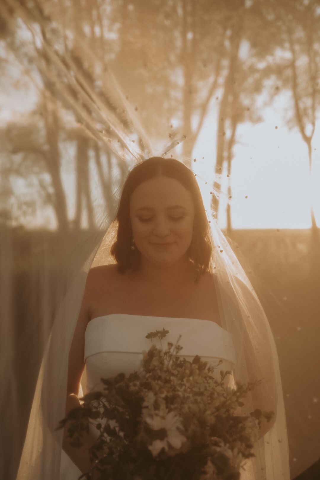 Ethereal golden hour portrait with delicate floral bouquet.