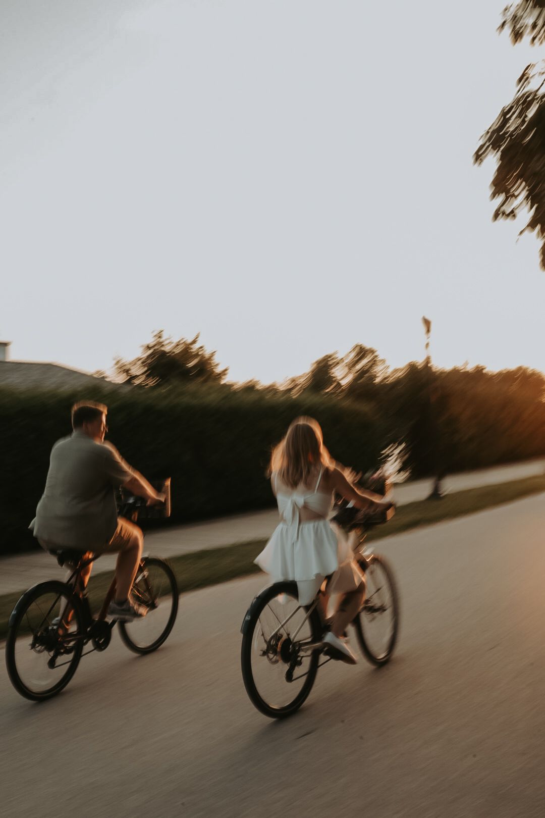 A couple rides bikes together on a winding path during dusk.