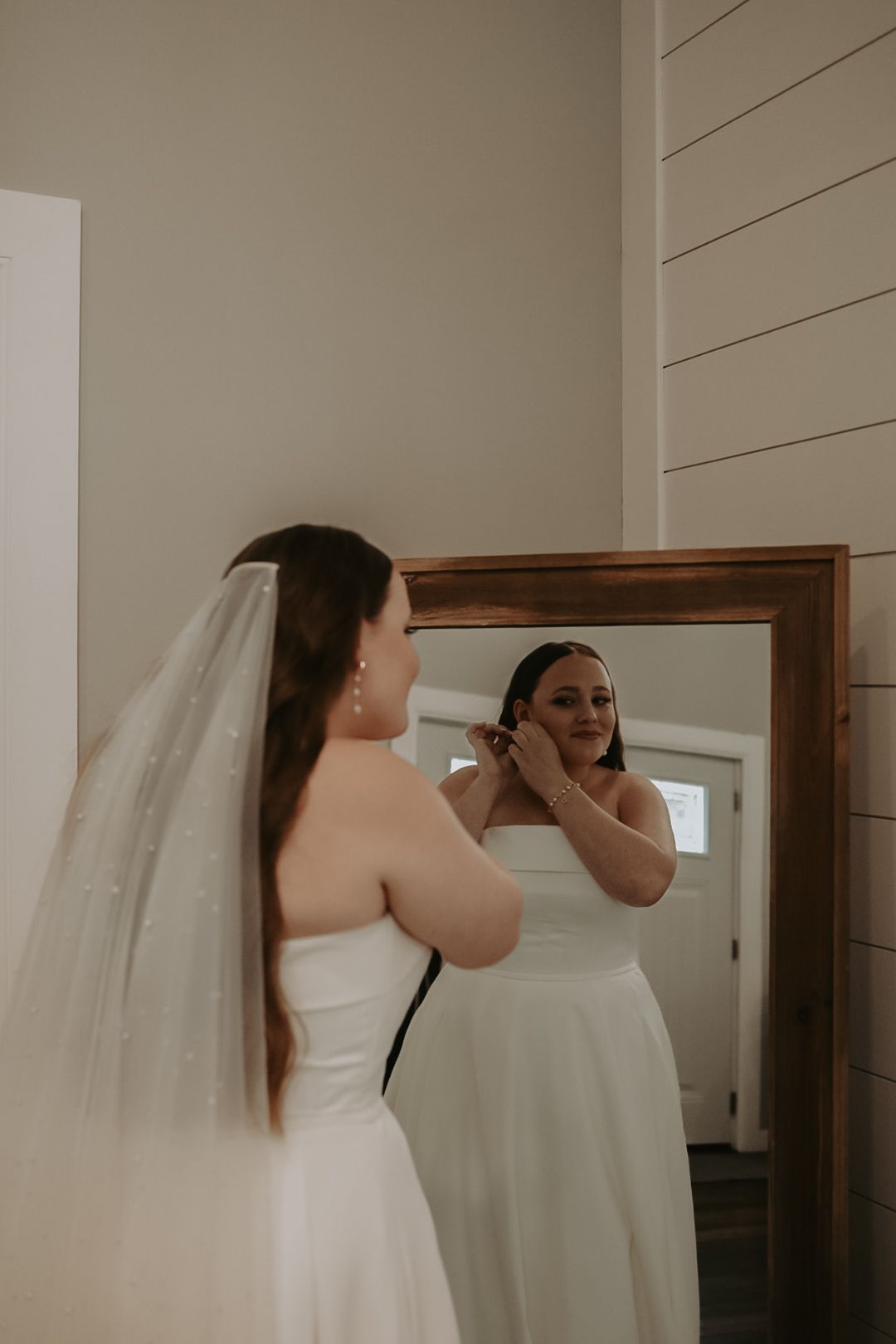Wedding preparation scene showing reflections in a wooden-framed mirror.