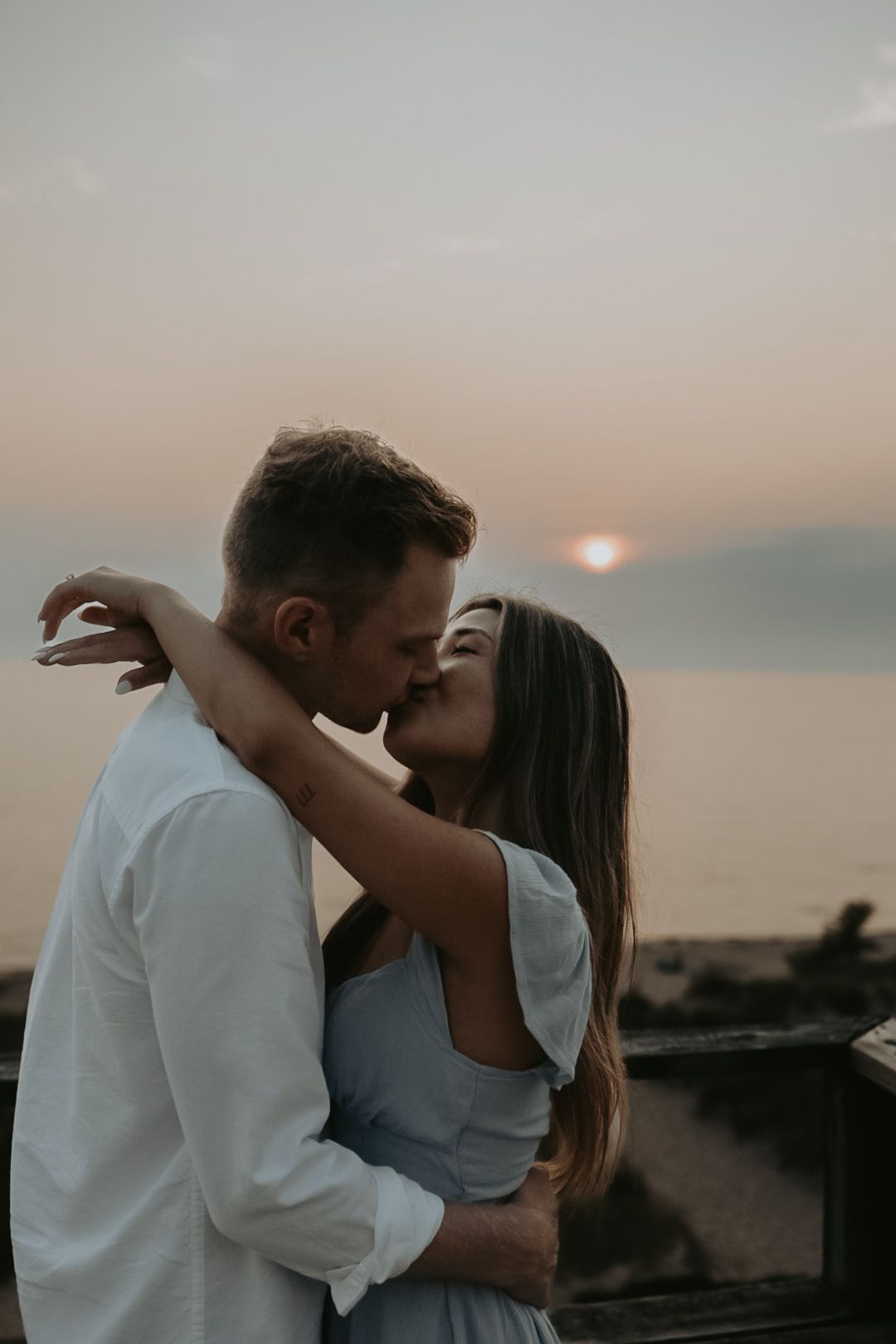 A romantic sunset moment between a couple on a beach overlook.