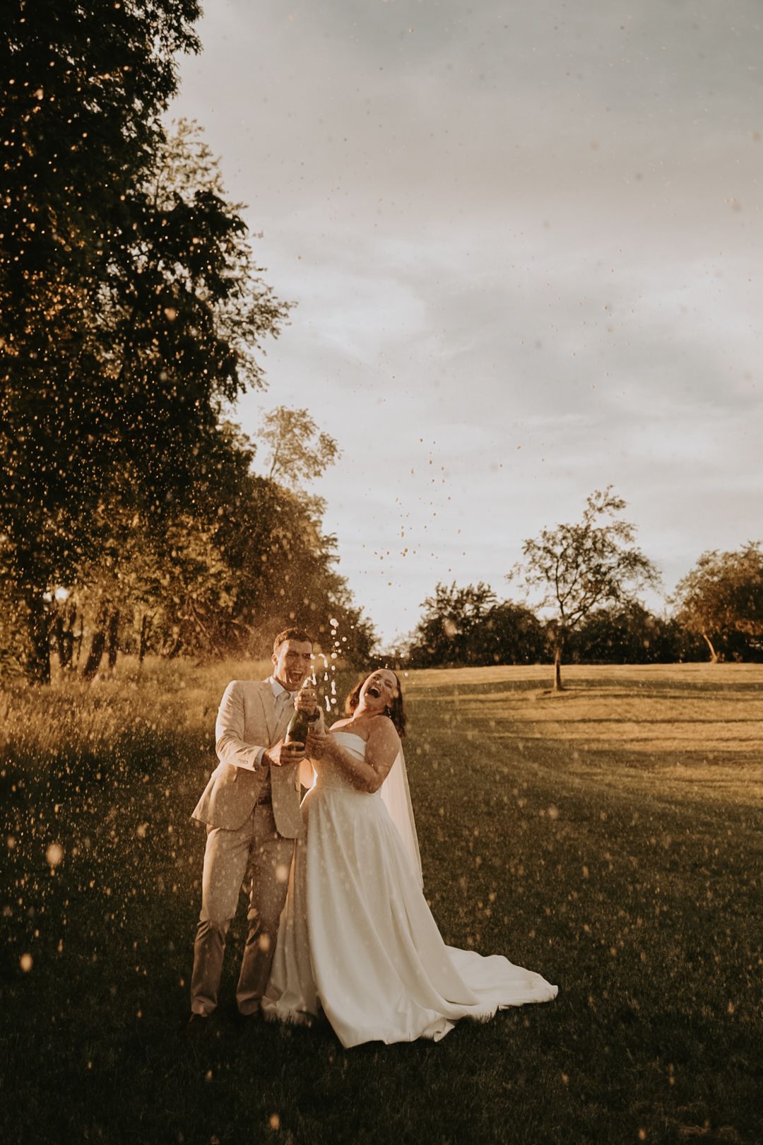A romantic sunset wedding photoshoot in a golden field with soft glowing light.