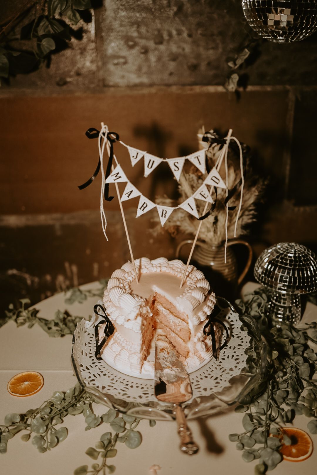 Wedding cake decorated with delicate bunting flags and dried citrus slices on a vintage doily.