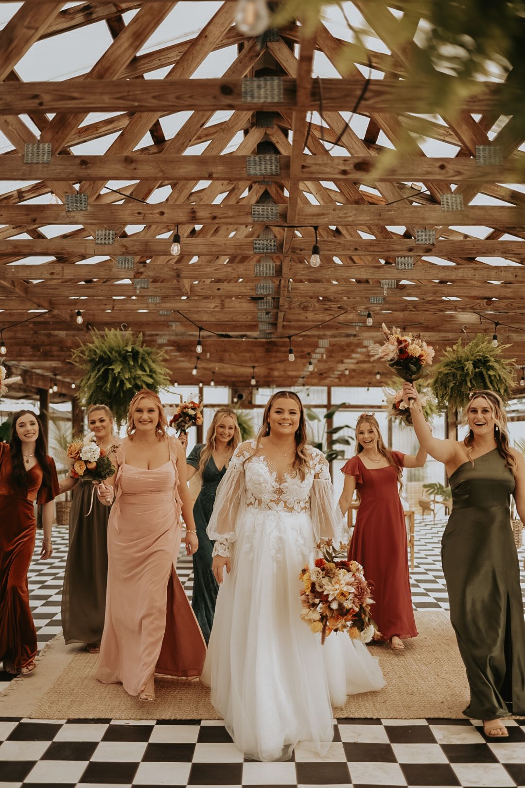 Wedding celebration under exposed wooden beams with checkered floor and hanging plants.