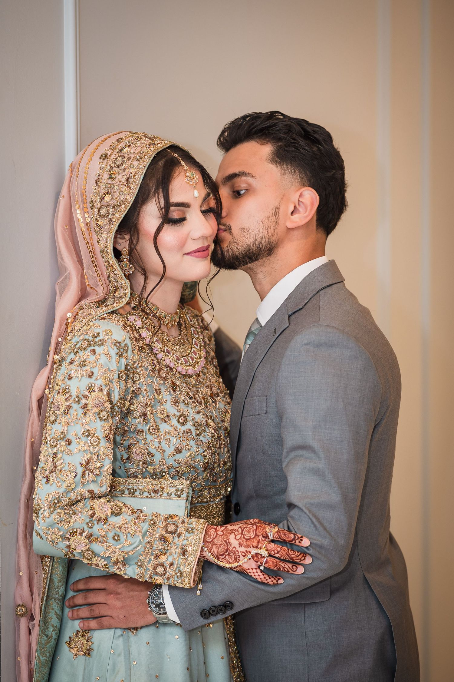 Intimate moment between couple in traditional South Asian wedding attire.