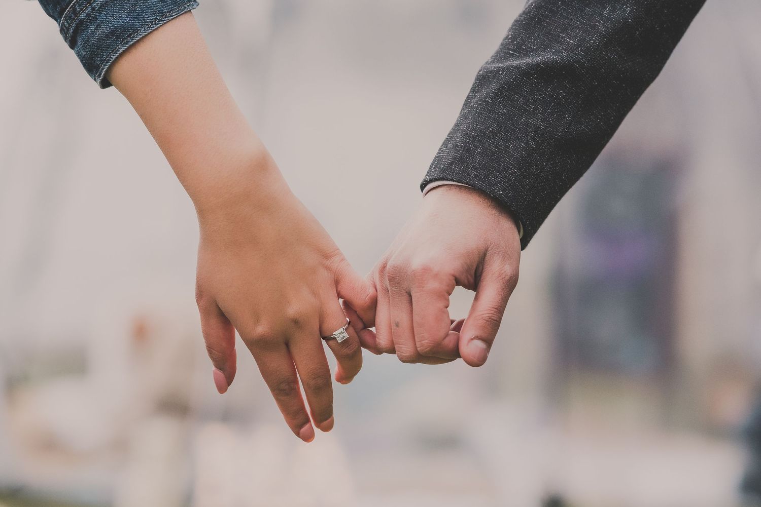 Wedding couple holds hands in front of rustic wooden barn backdrop.