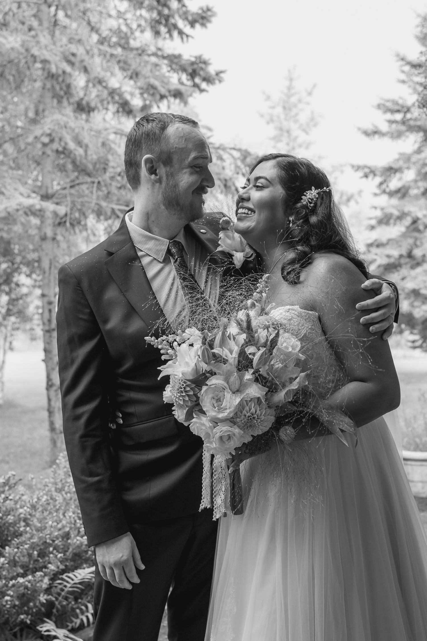 A joyful wedding couple shares intimate candid moments in a series of black and white outdoor portraits.