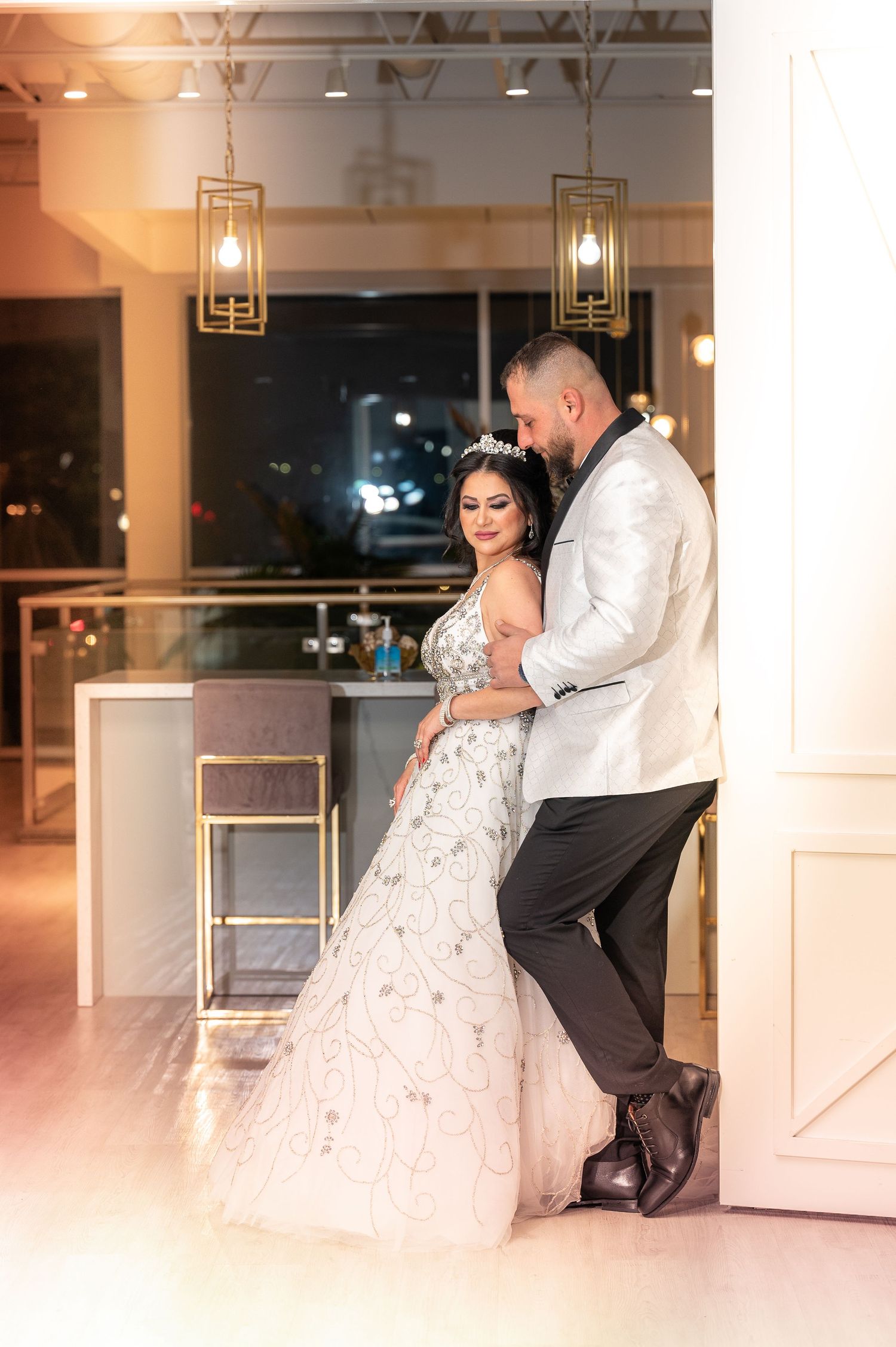 Wedding couple in white attire sharing intimate dance moments in an elegant venue.