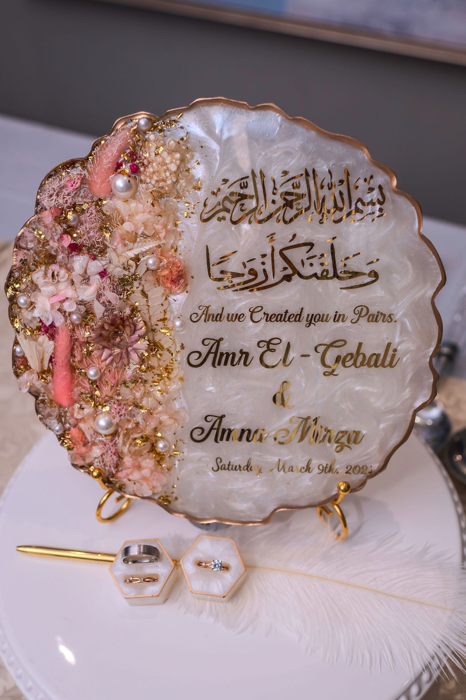 Ornate wedding place cards with Arabic calligraphy and floral designs in gold and pink.