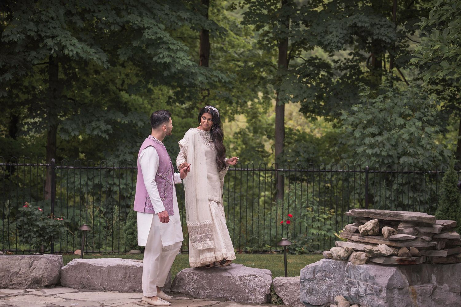 A romantic outdoor photoshoot featuring soft pink and white attire against a natural garden backdrop.