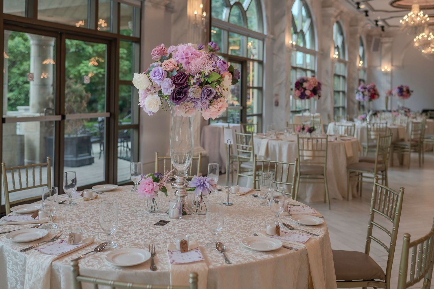 Elegant wedding reception hall with crystal chandeliers and round tables set for dining.