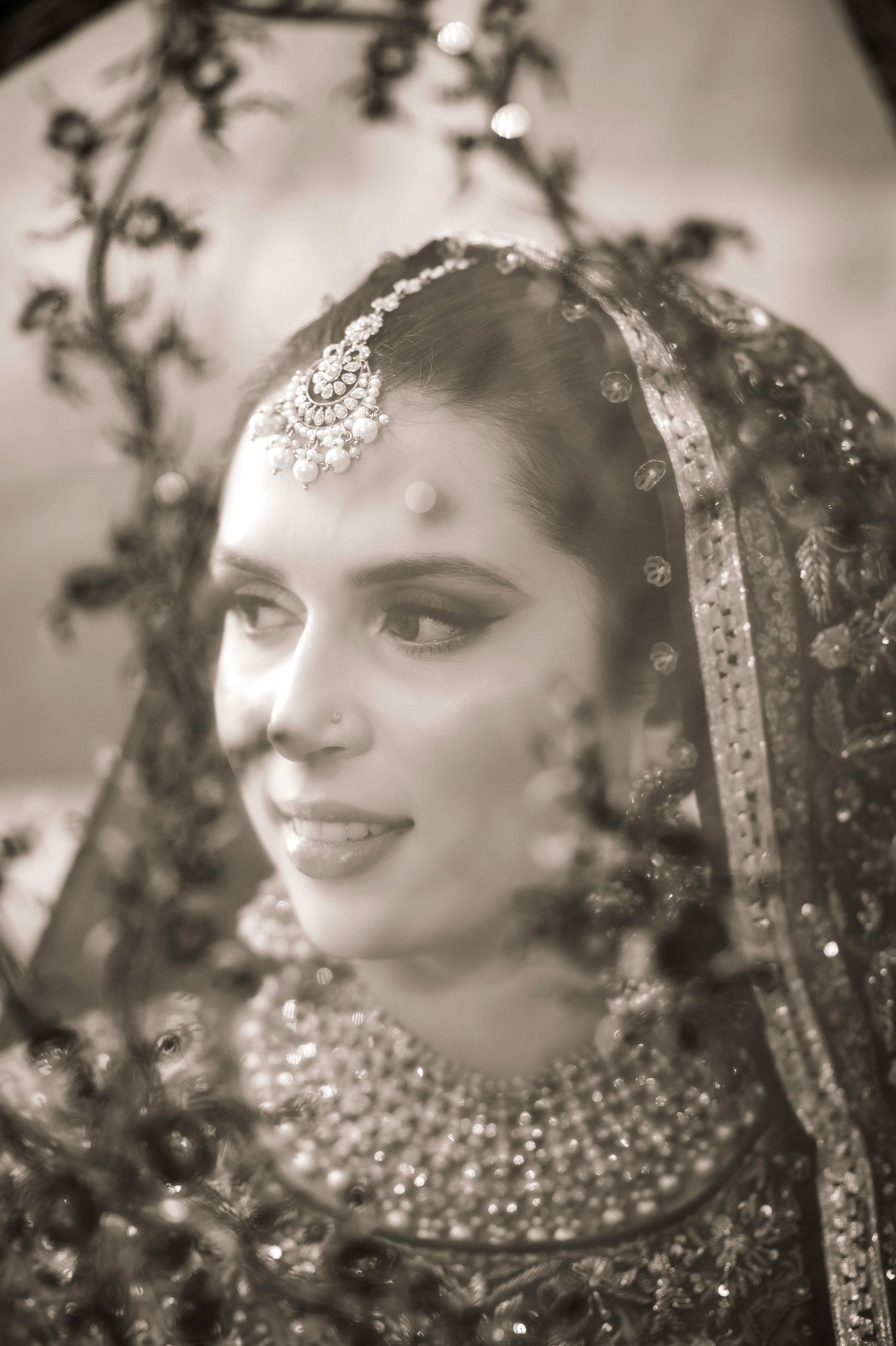 A close-up portrait showing intricate bridal jewelry and traditional South Asian wedding attire.