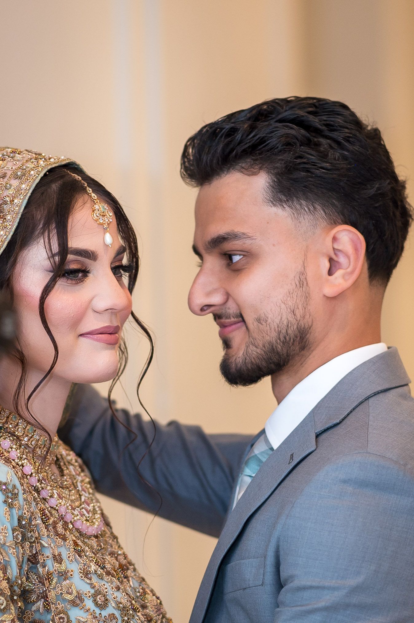 Newlyweds in traditional South Asian wedding attire exchanging loving glances in a romantic photoshoot.