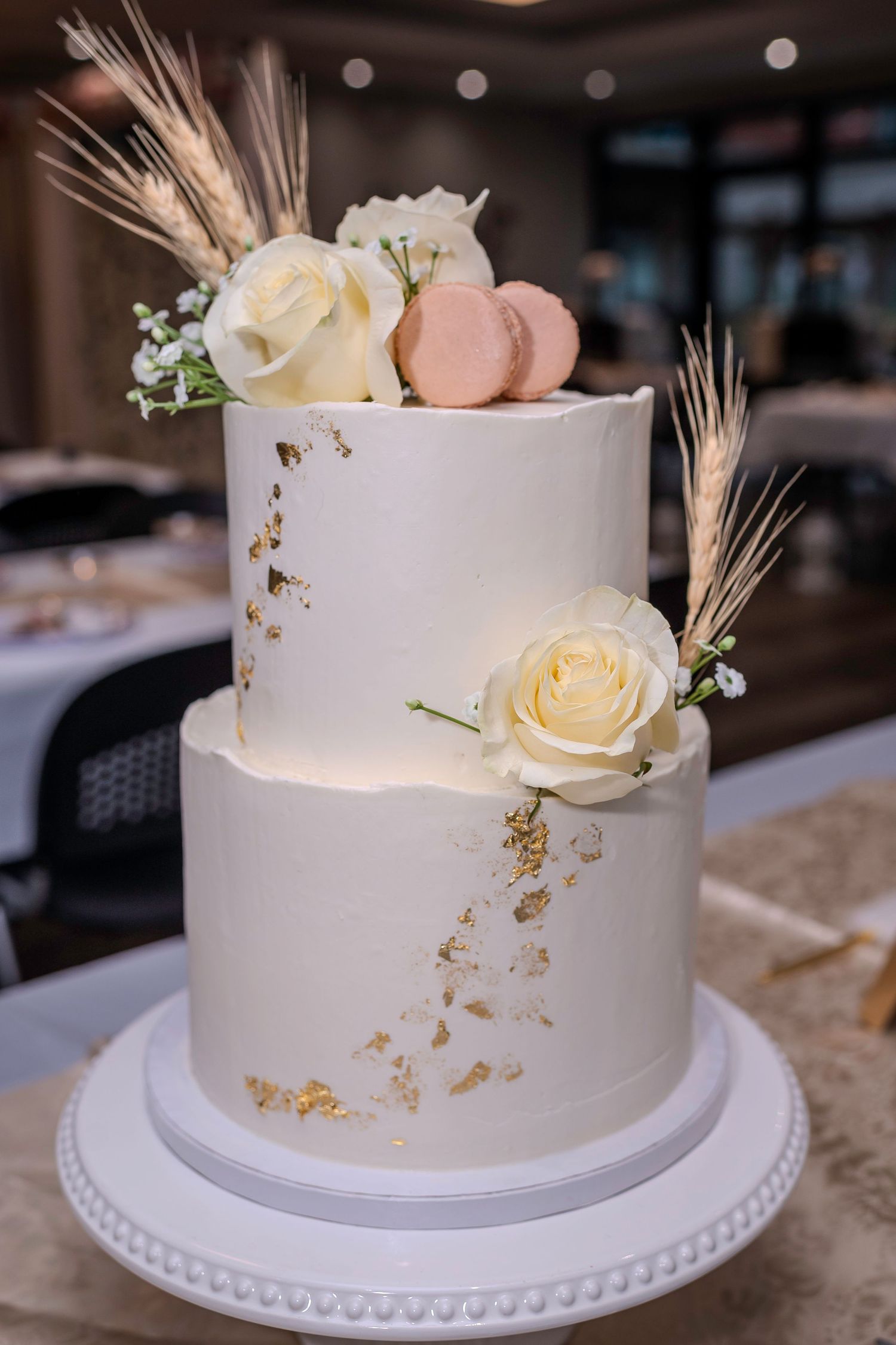 Simple white wedding cake with delicate gold accents and fresh white roses.