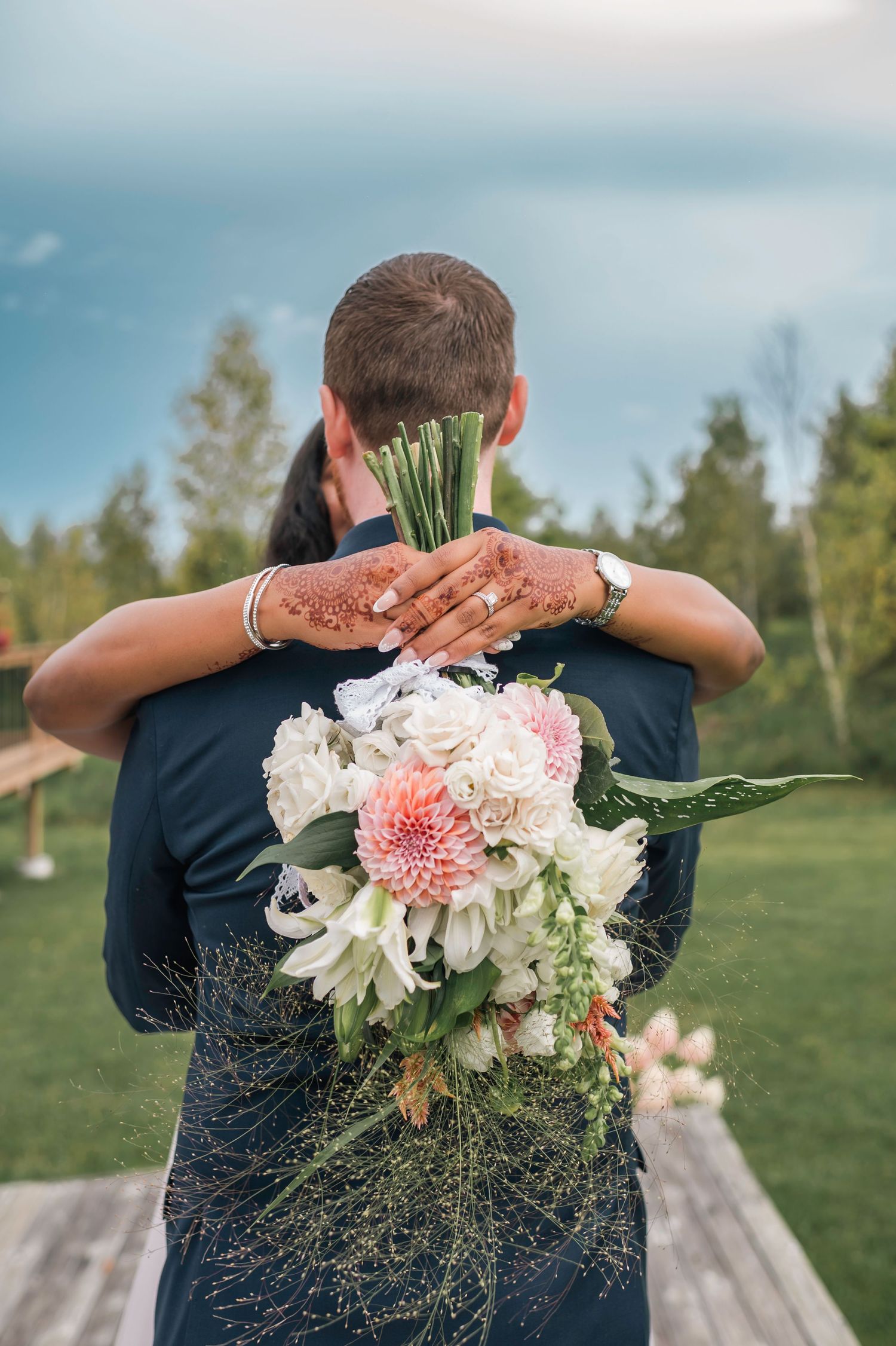 A sequence of photos showing a bouquet of pink and white flowers held against a navy blue dress with a green outdoor backdrop.