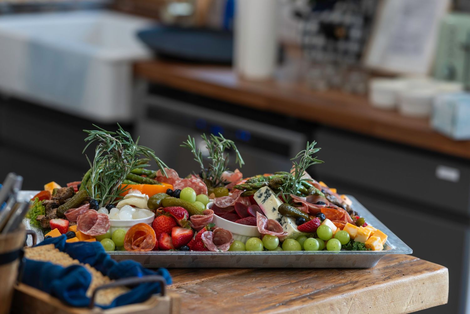 Fresh colorful vegetables and ingredients arranged on wooden cutting boards in a kitchen setting.