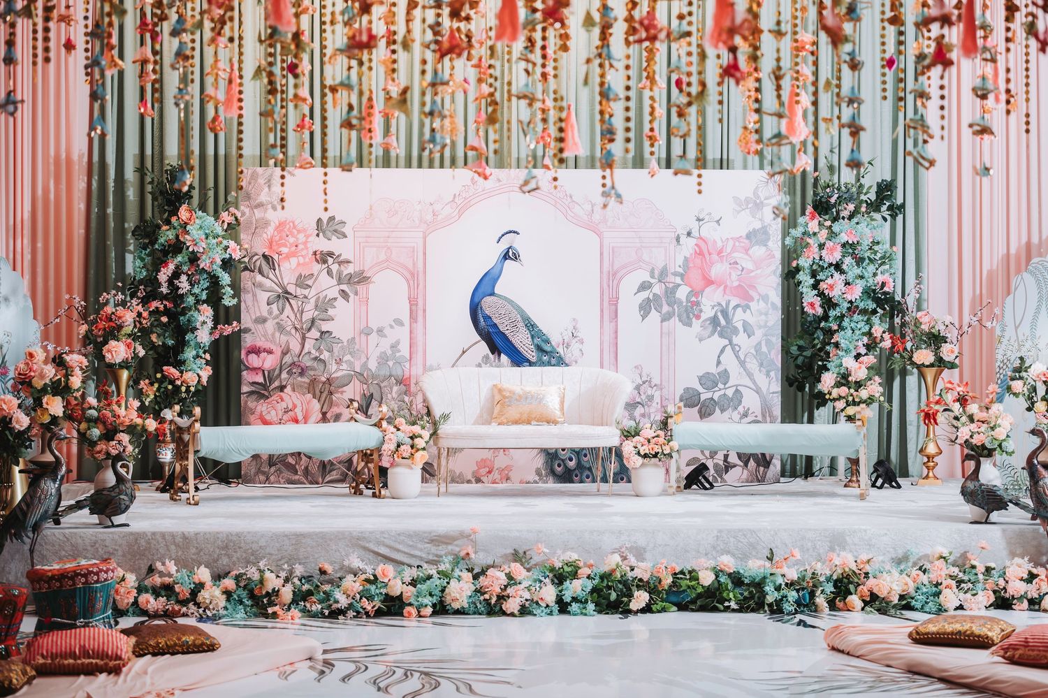 Panoramic view of an elegant wedding stage with floral decorations and peacock motif artwork.