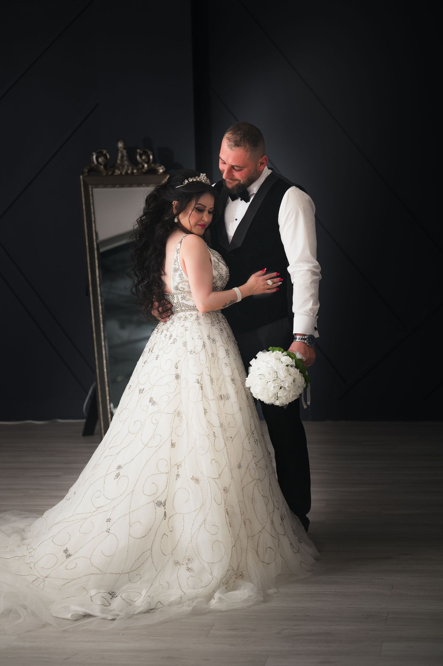 A romantic first dance between newlyweds in a ballroom with dramatic lighting and a flowing white wedding gown.