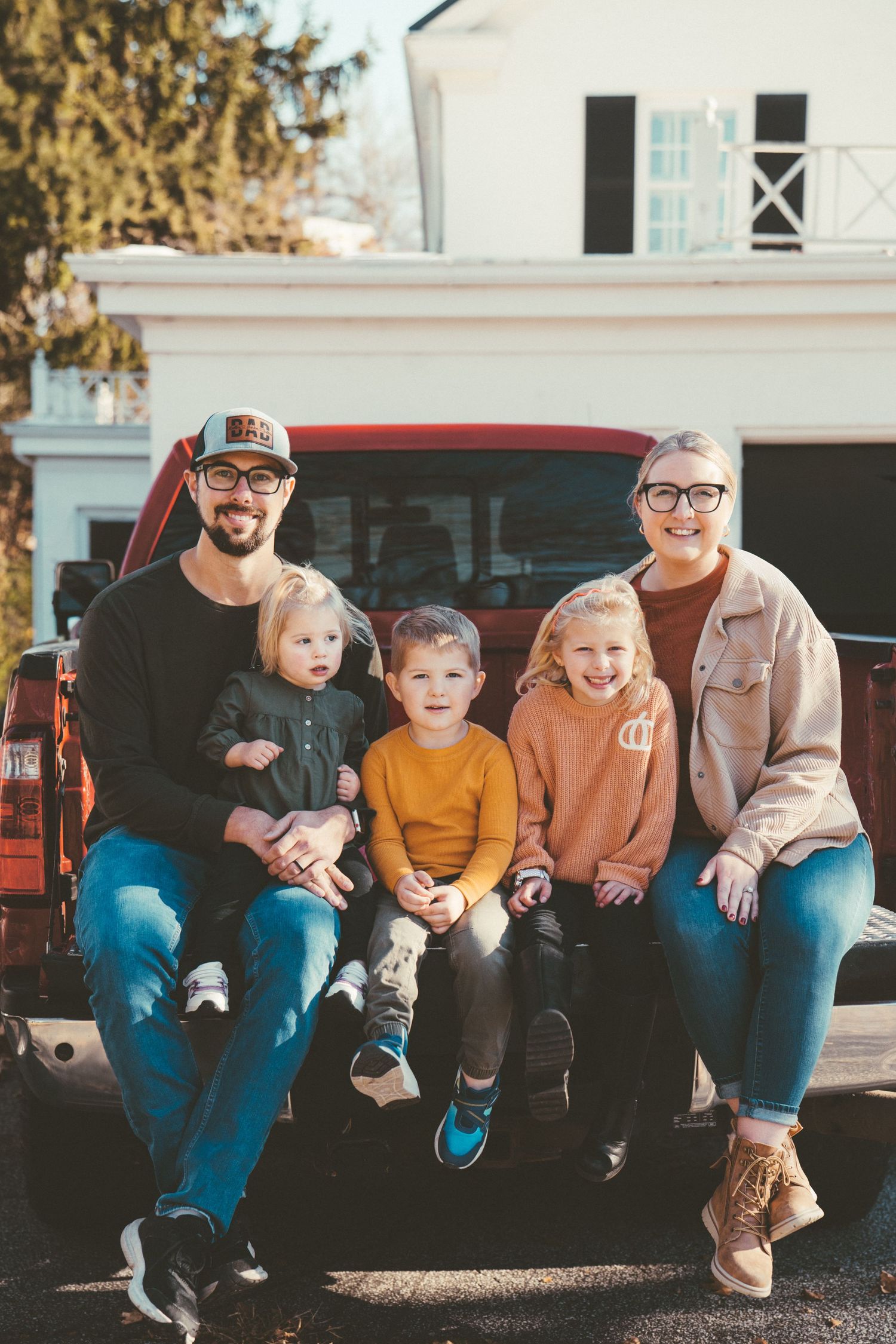 Family sitting together on truck tailgate in casual autumn setting.
