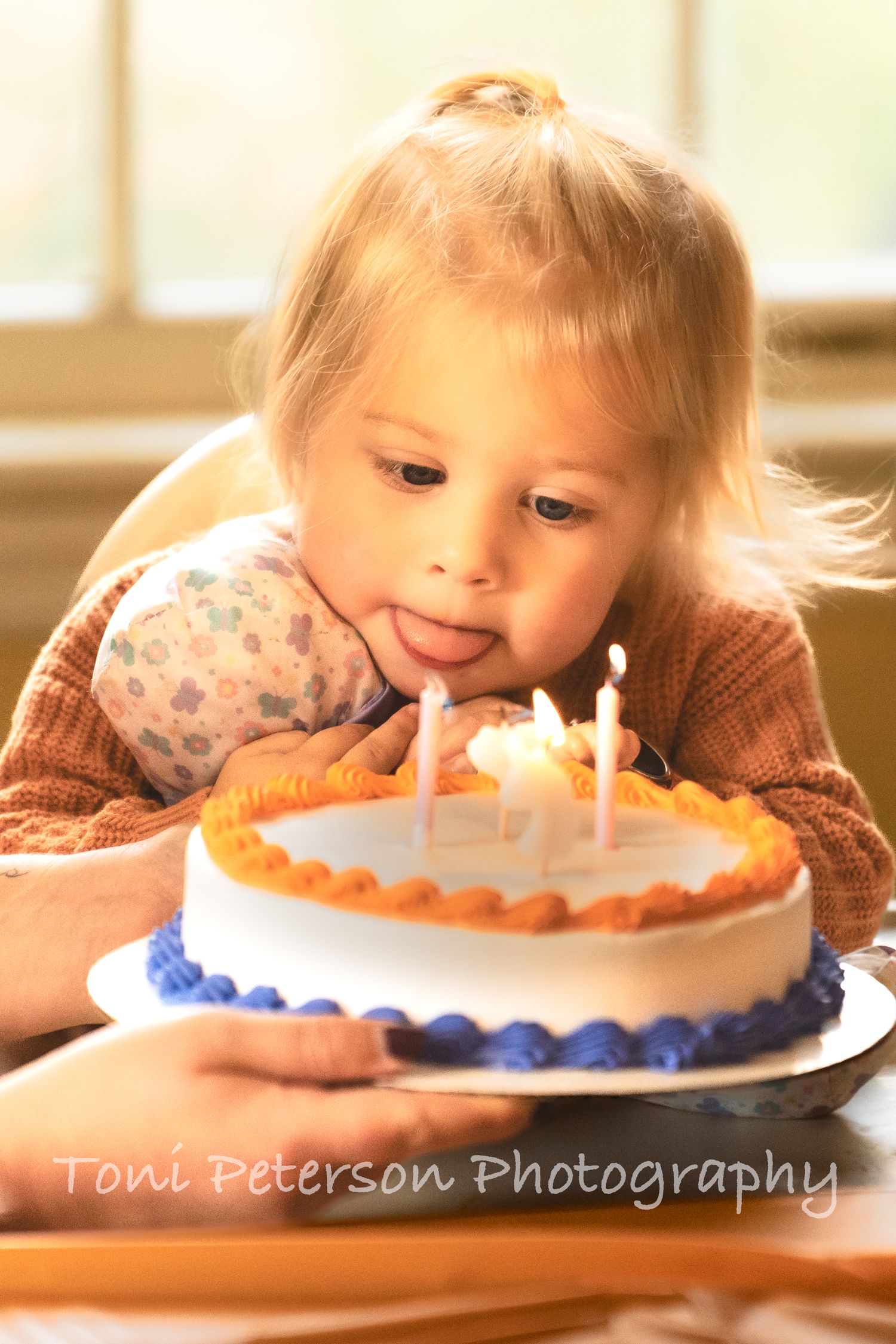 Child blowing out birthday candles on decorated cake.