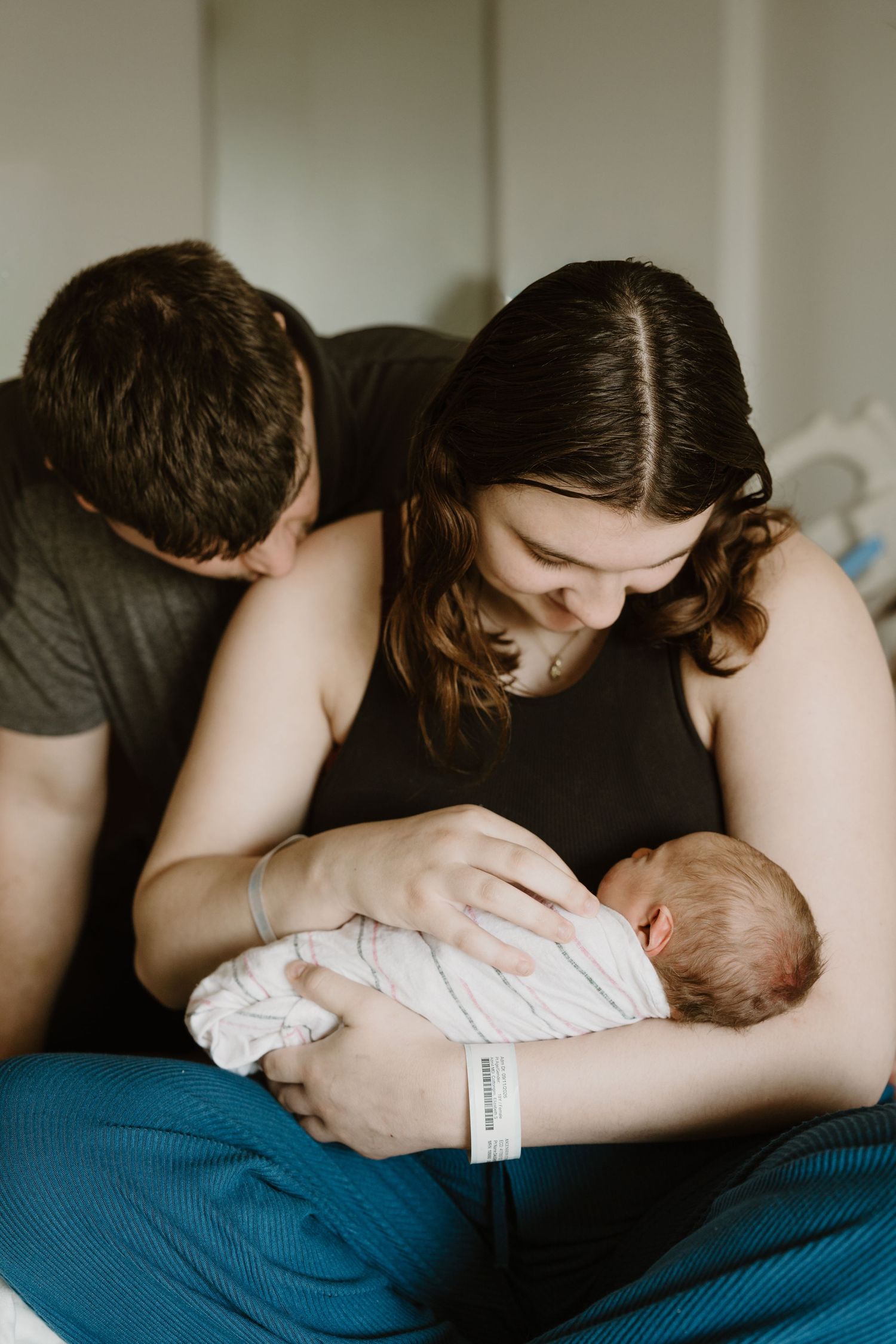 New parents lovingly cradling their swaddled newborn baby together during Fresh 48 in-hospital newborn photography session Miami County IN