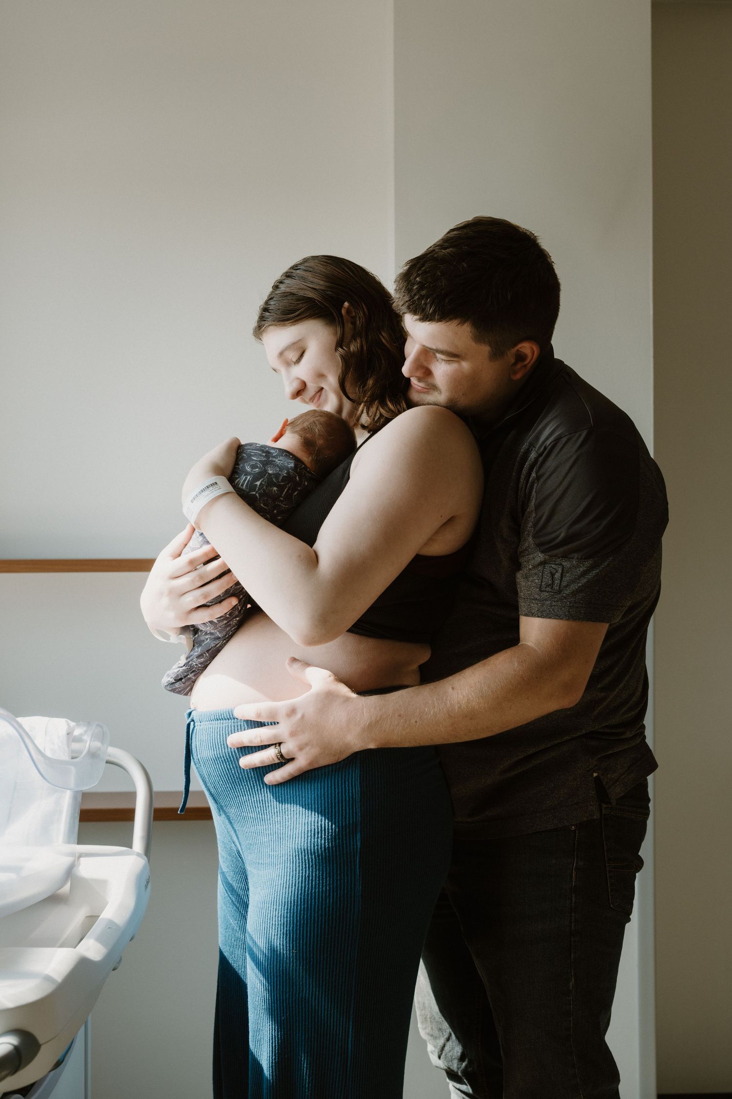Authentic family portrait showing father holding mom holding new newborn during Fresh 48 hospital photography session in North Central IN