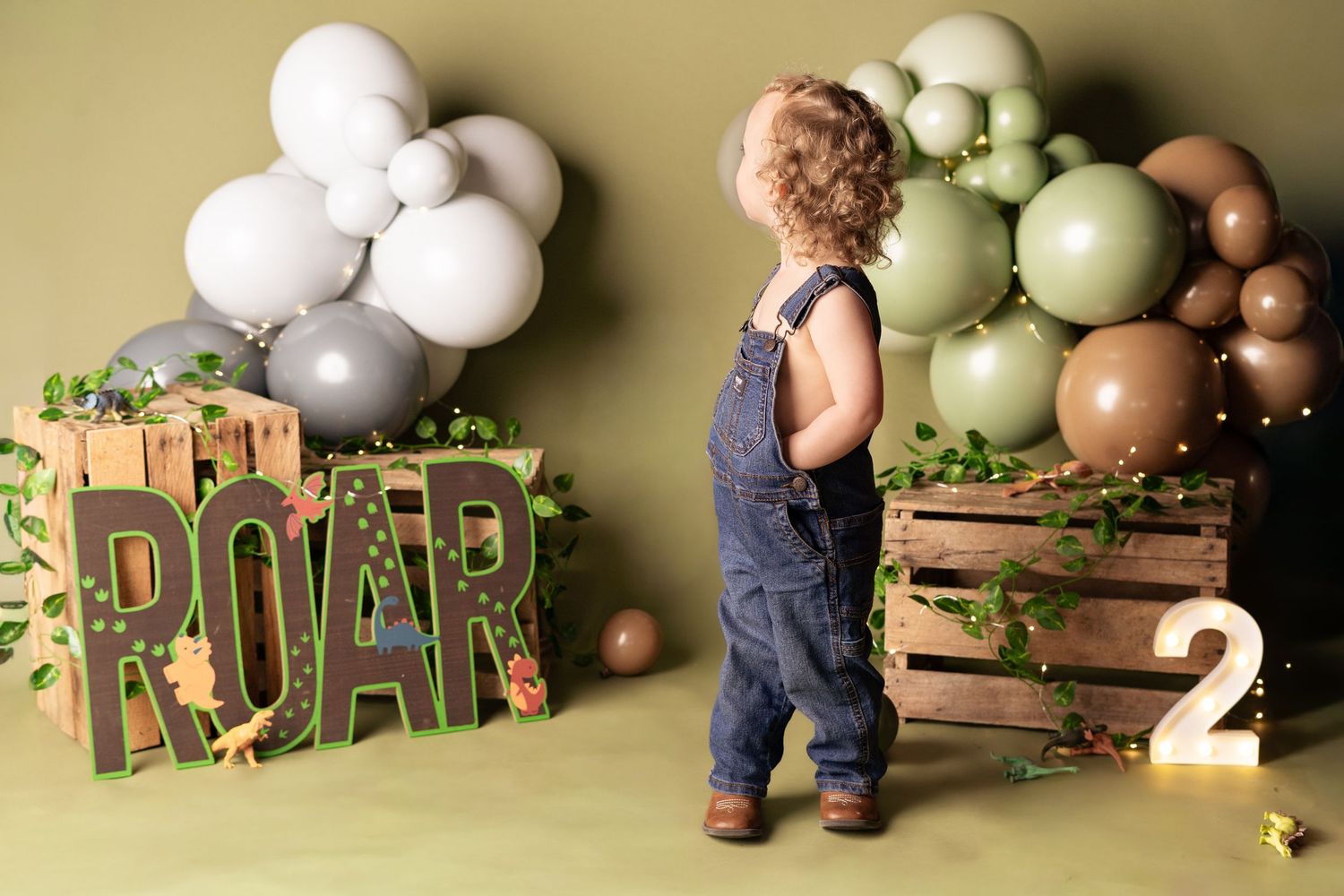 Rustic wooden crates decorated with balloon garlands and safari-themed decor for a party setup.