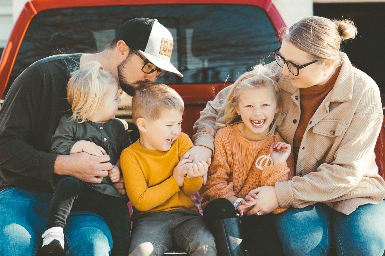 Candid moment of family bonding and laughter on pickup truck bed.