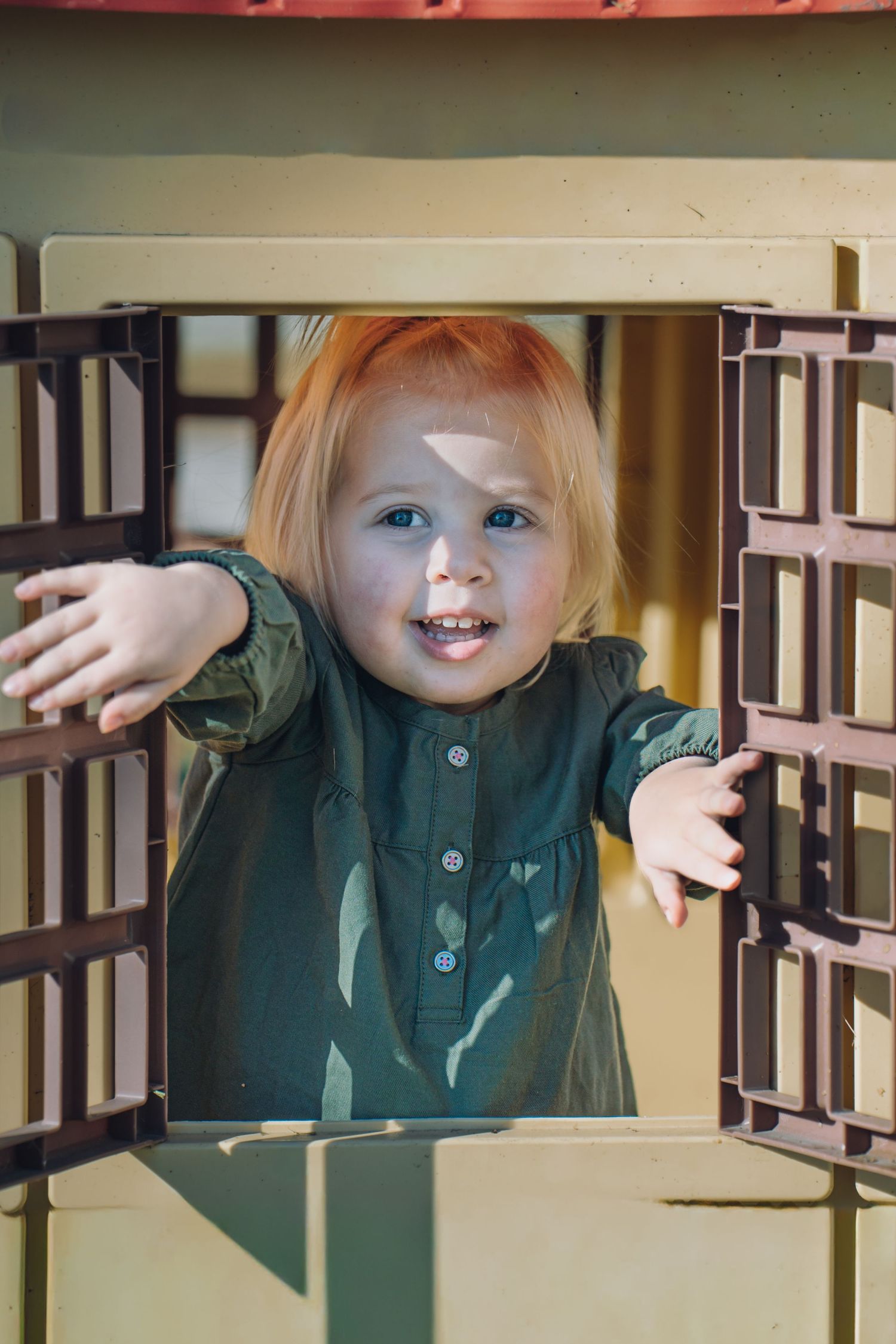 Indoor portraits showing playful expressions through wooden railings.