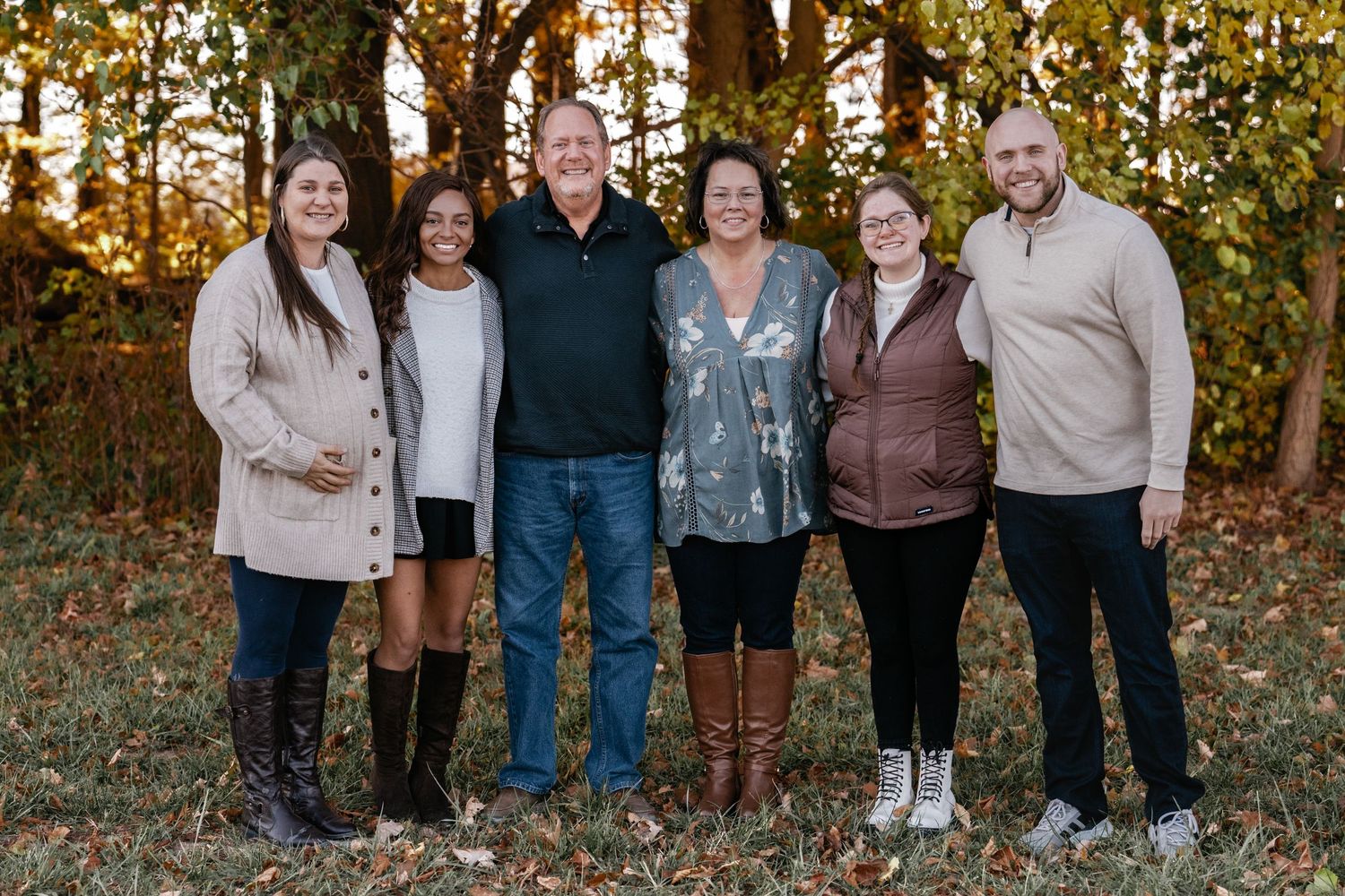Extended family members gather for group photos in wooded autumn setting.