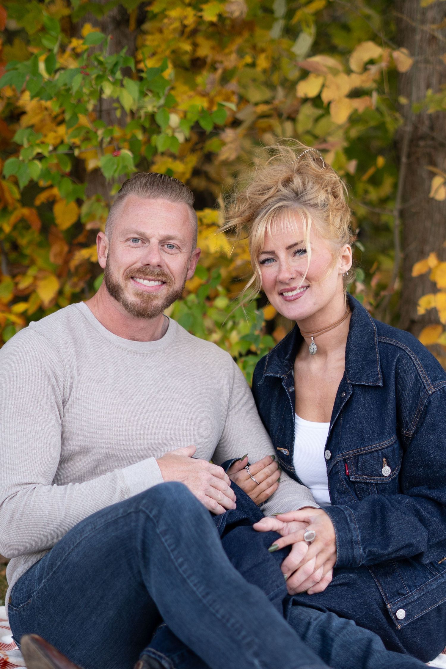 Couple relaxing and sharing intimate moments during fall photo session outdoors.