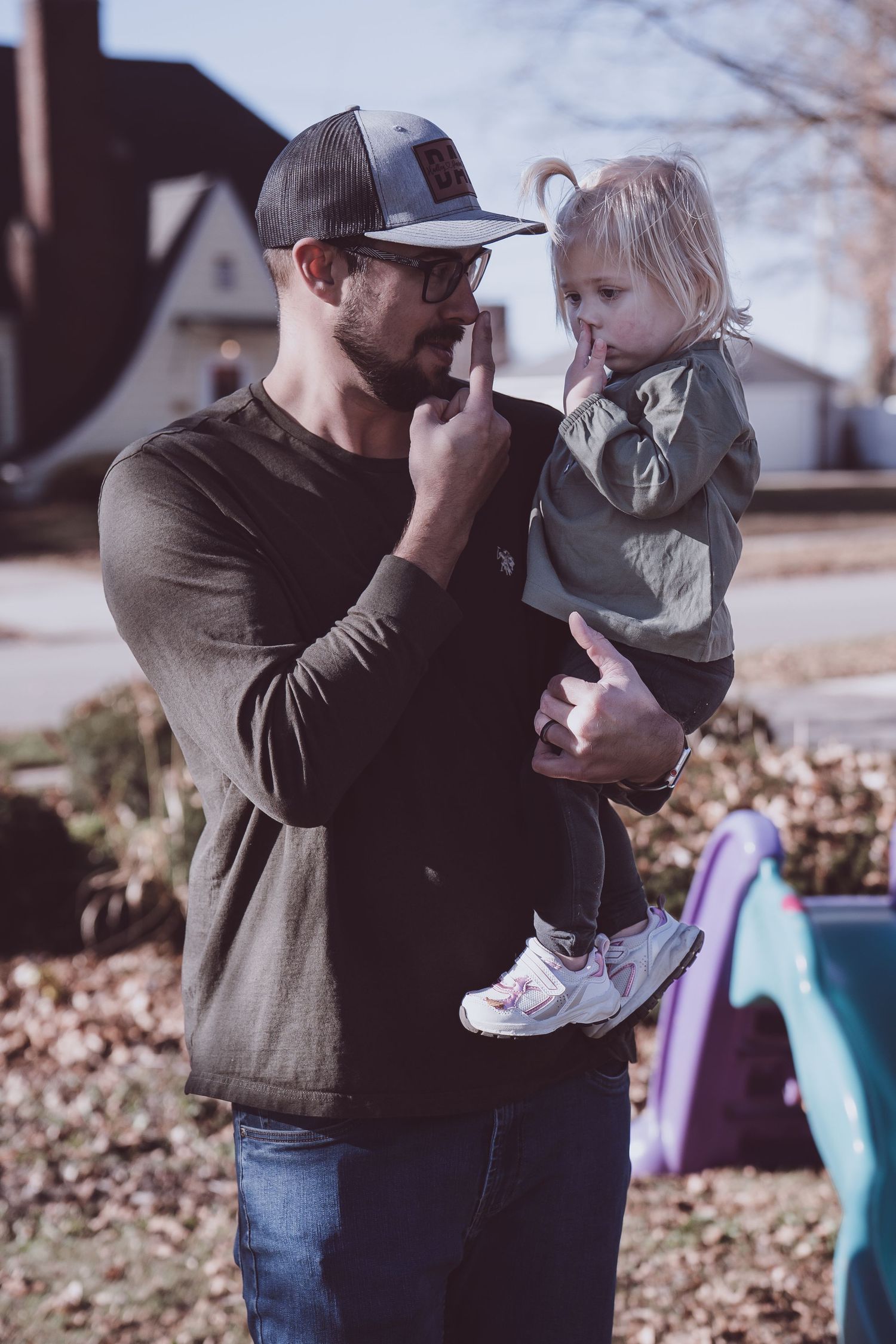 Adult and toddler share a tender moment outdoors during fall season.