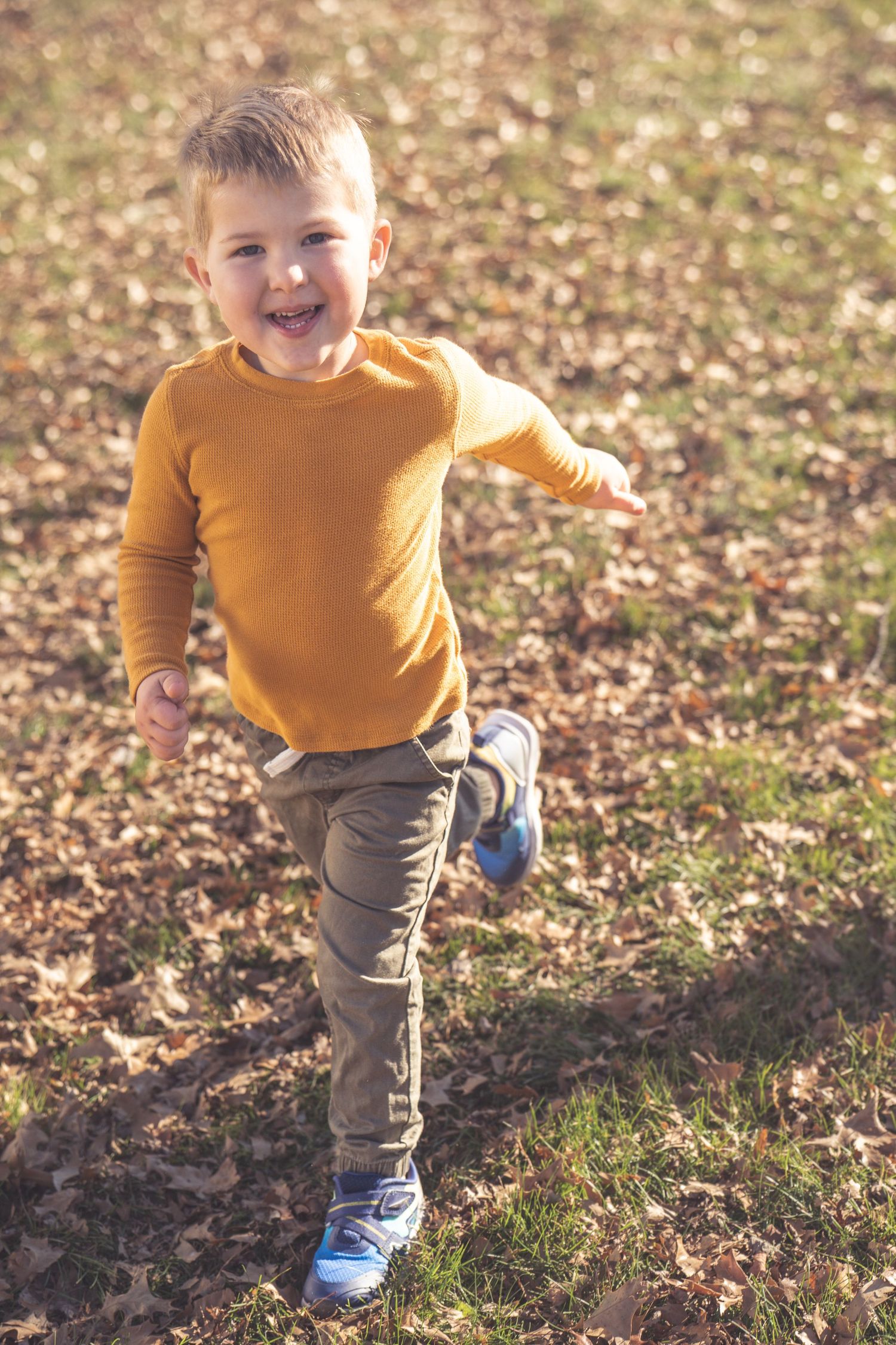 Action shots in a mustard yellow sweater running through fallen leaves.