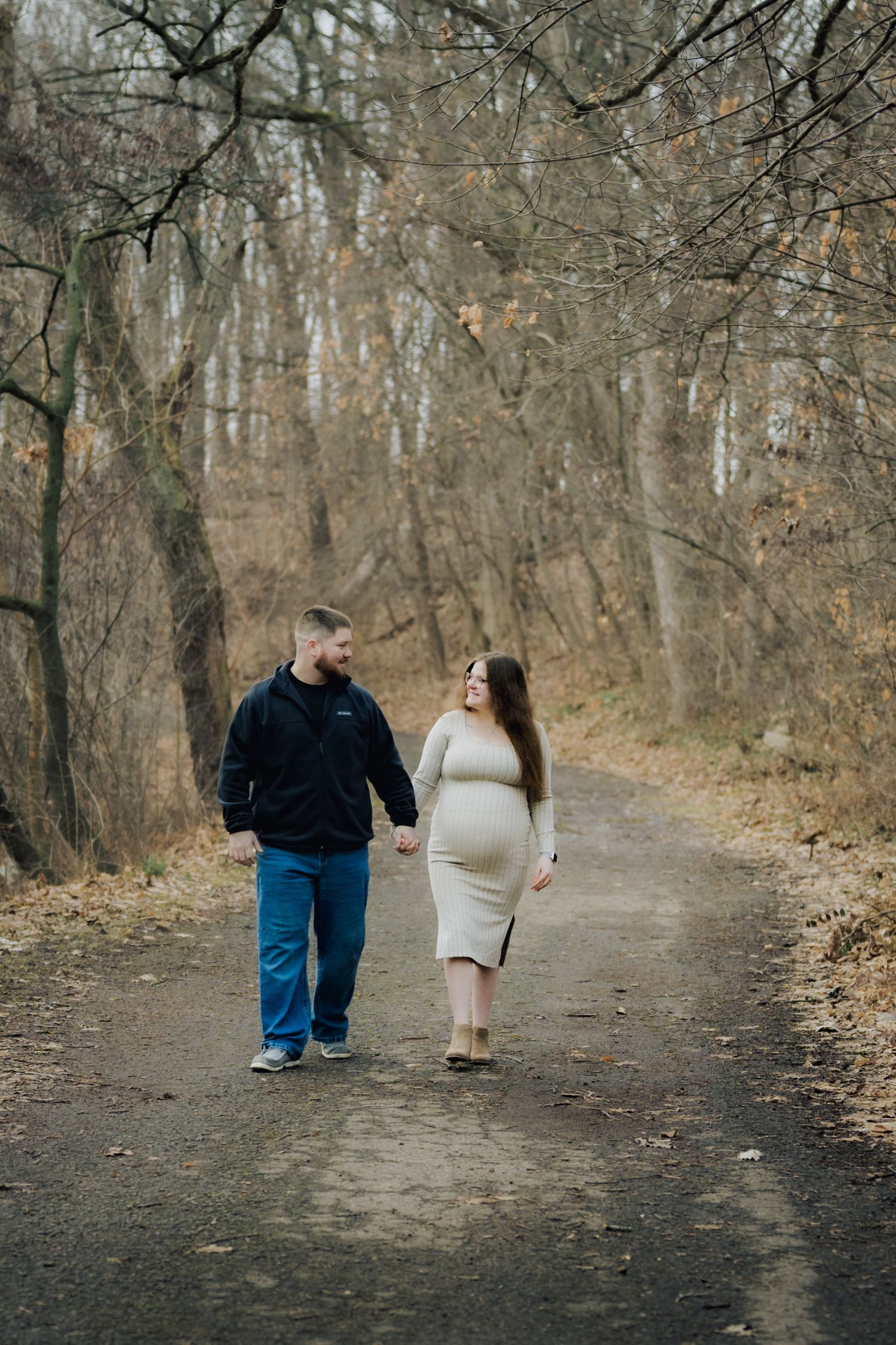 Wide angle shot of a couple walking down a tree-lined path in autumn.
