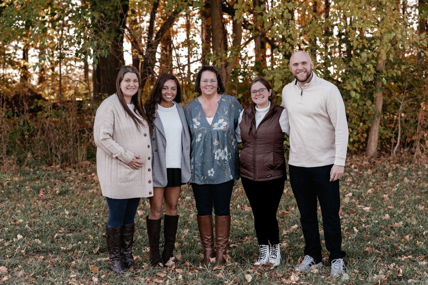 Extended family group poses together for outdoor portraits in autumn woodland setting.