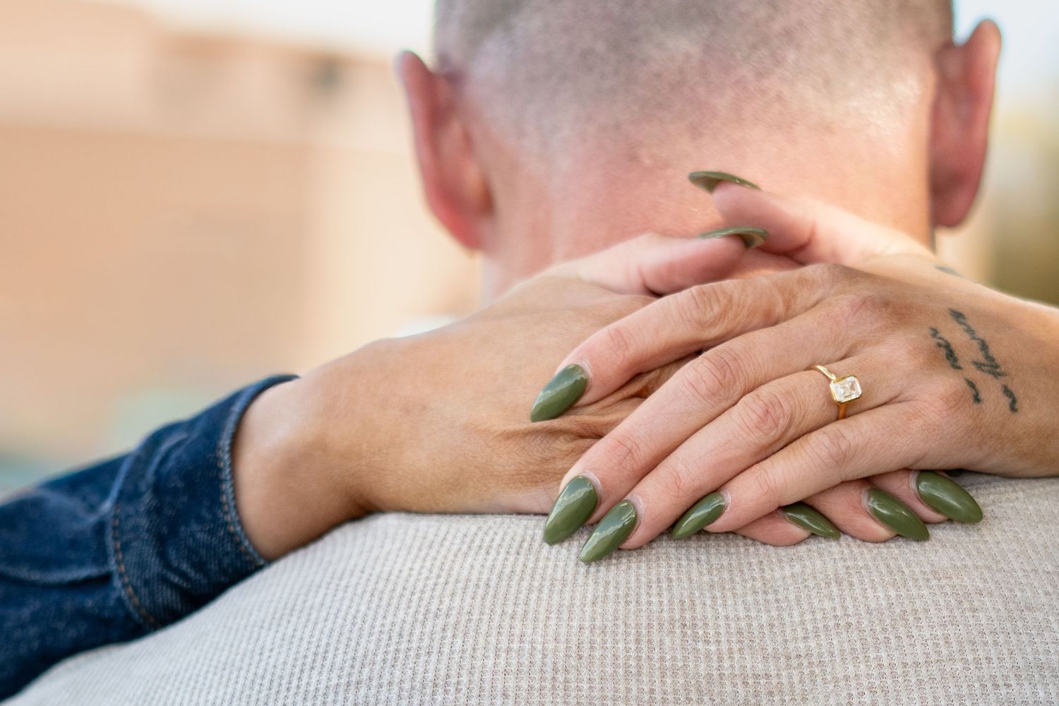 Close-up of hands with green nail polish resting gently on fabric.