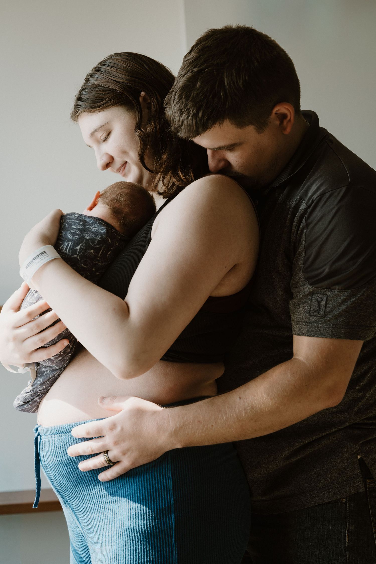 Candid family portrait by Bushel & a Peck Photography showing parents embracing their newborn during Fresh 48 session in North Central IN.