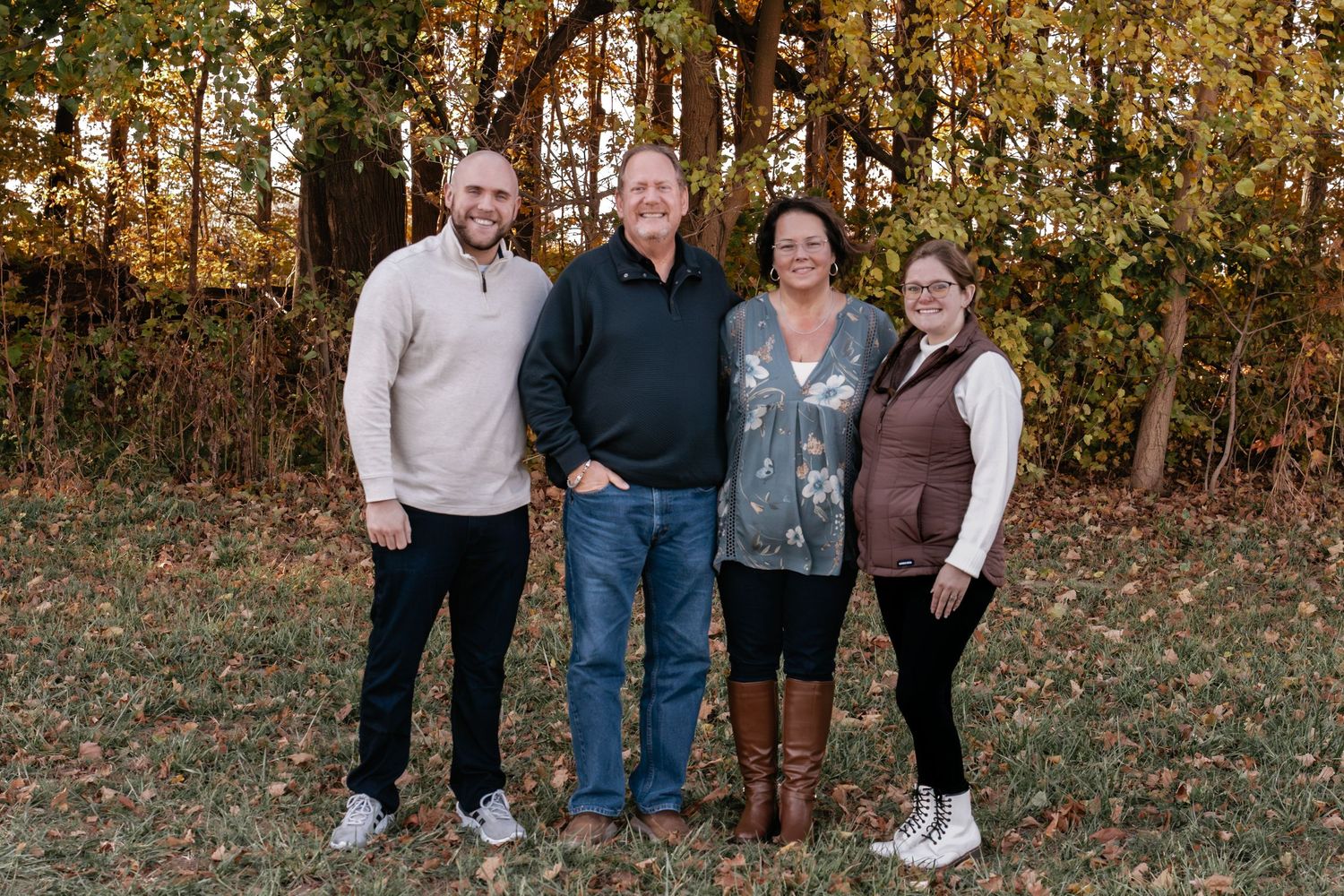 Large family group stands together for casual portraits among fall foliage.