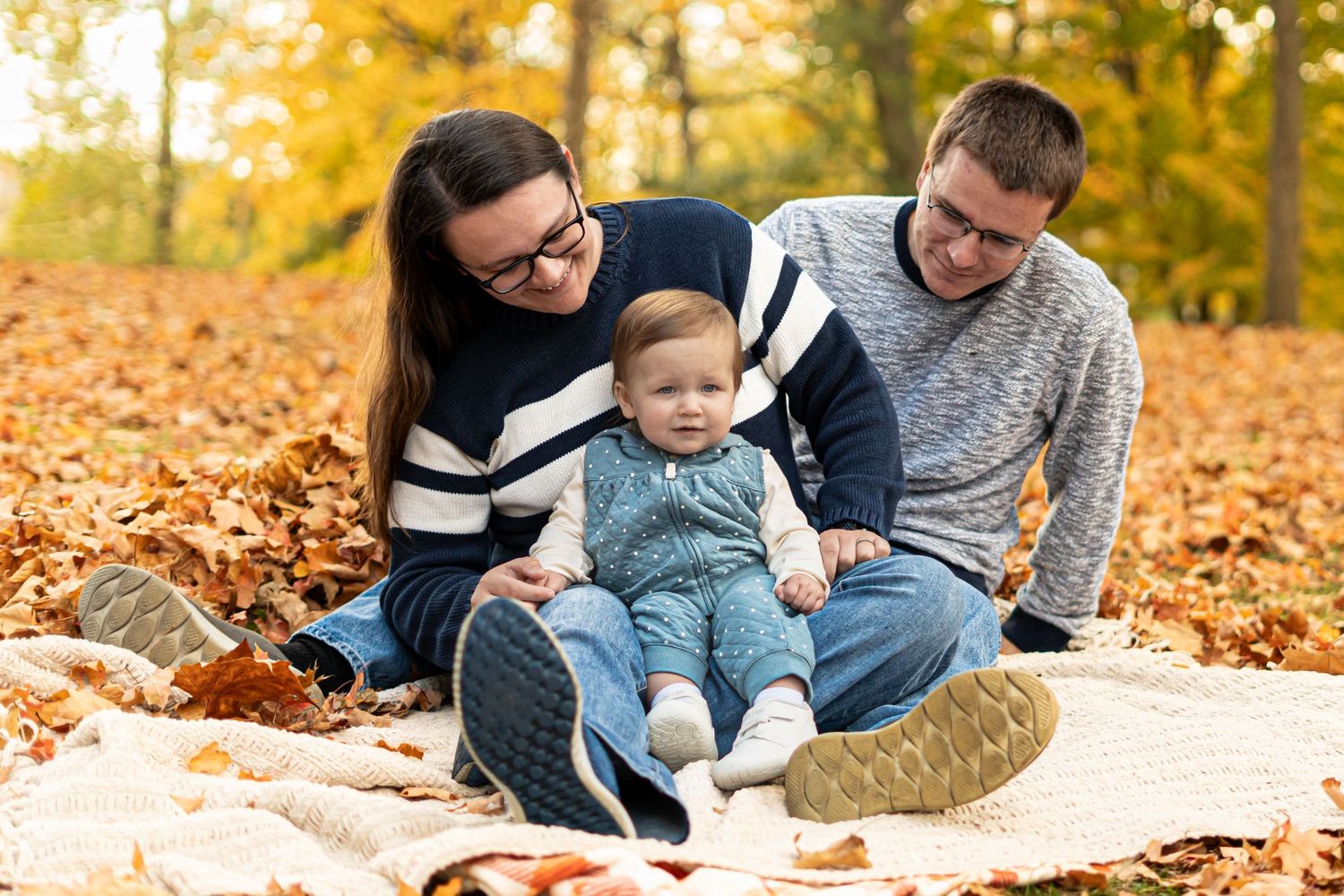 Casual family portrait session on blanket surrounded by golden fall foliage.