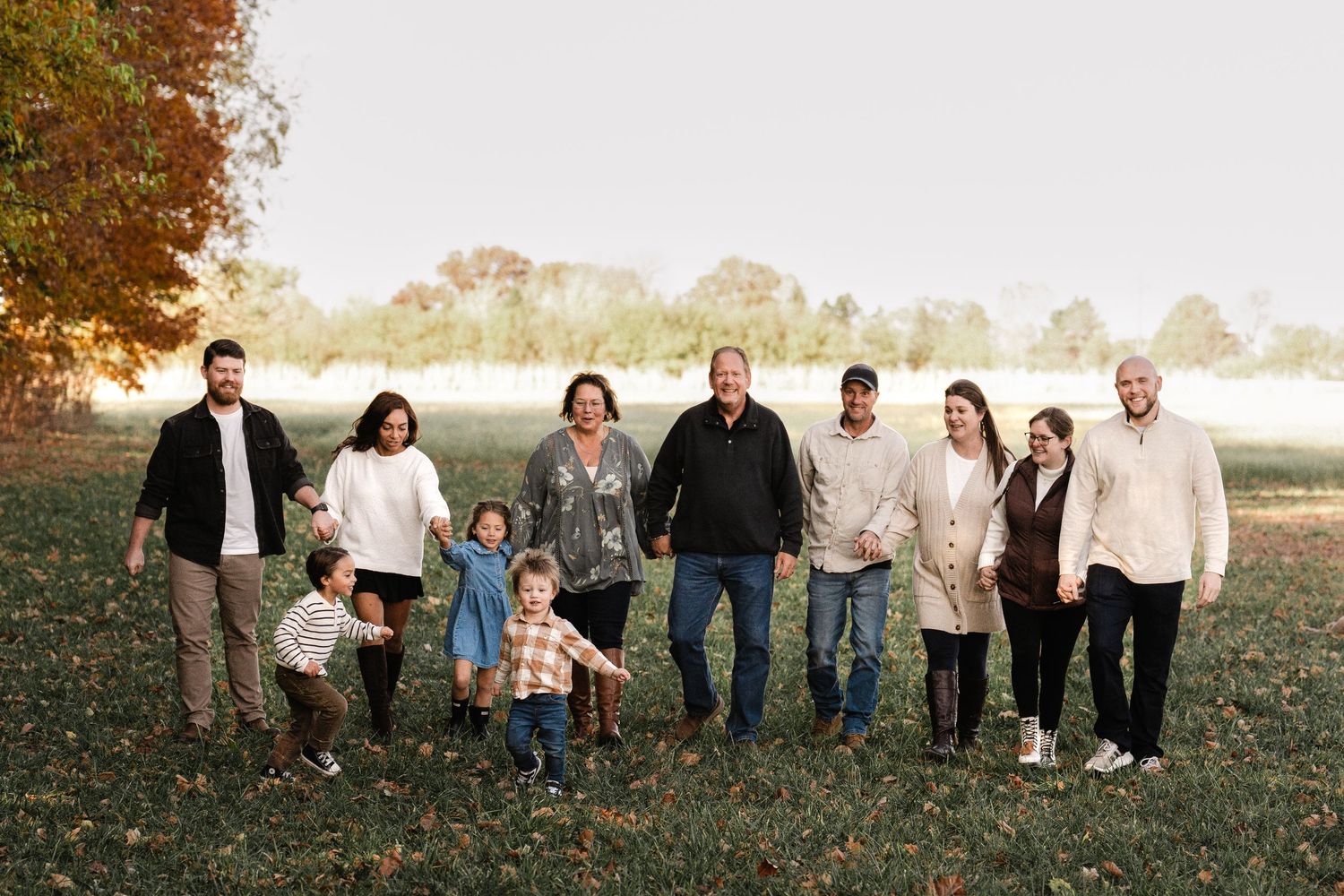 Large family group posing together on a hillside during autumn sunset.