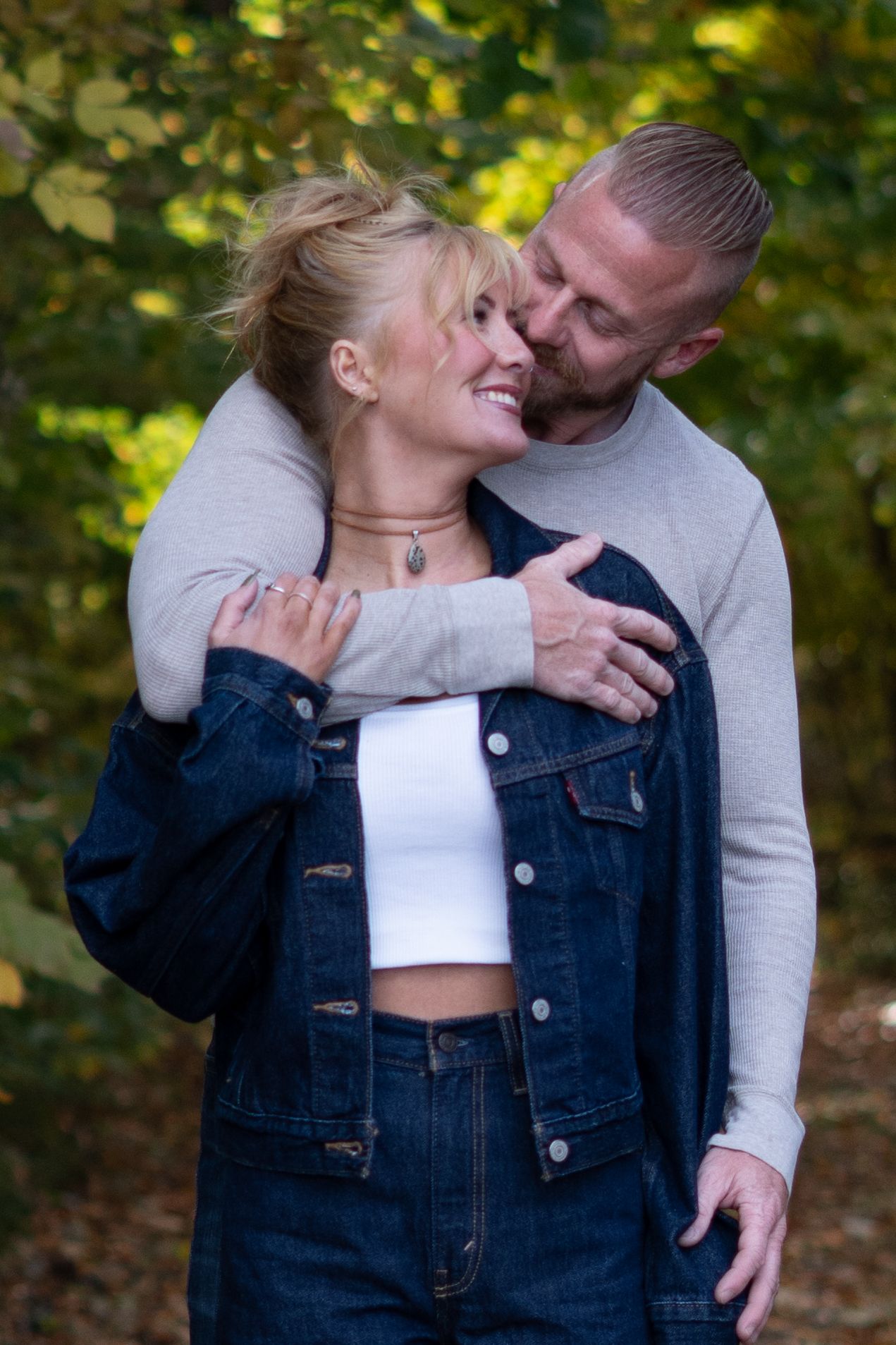 Candid romantic moments captured between couple wearing casual attire in autumn setting.