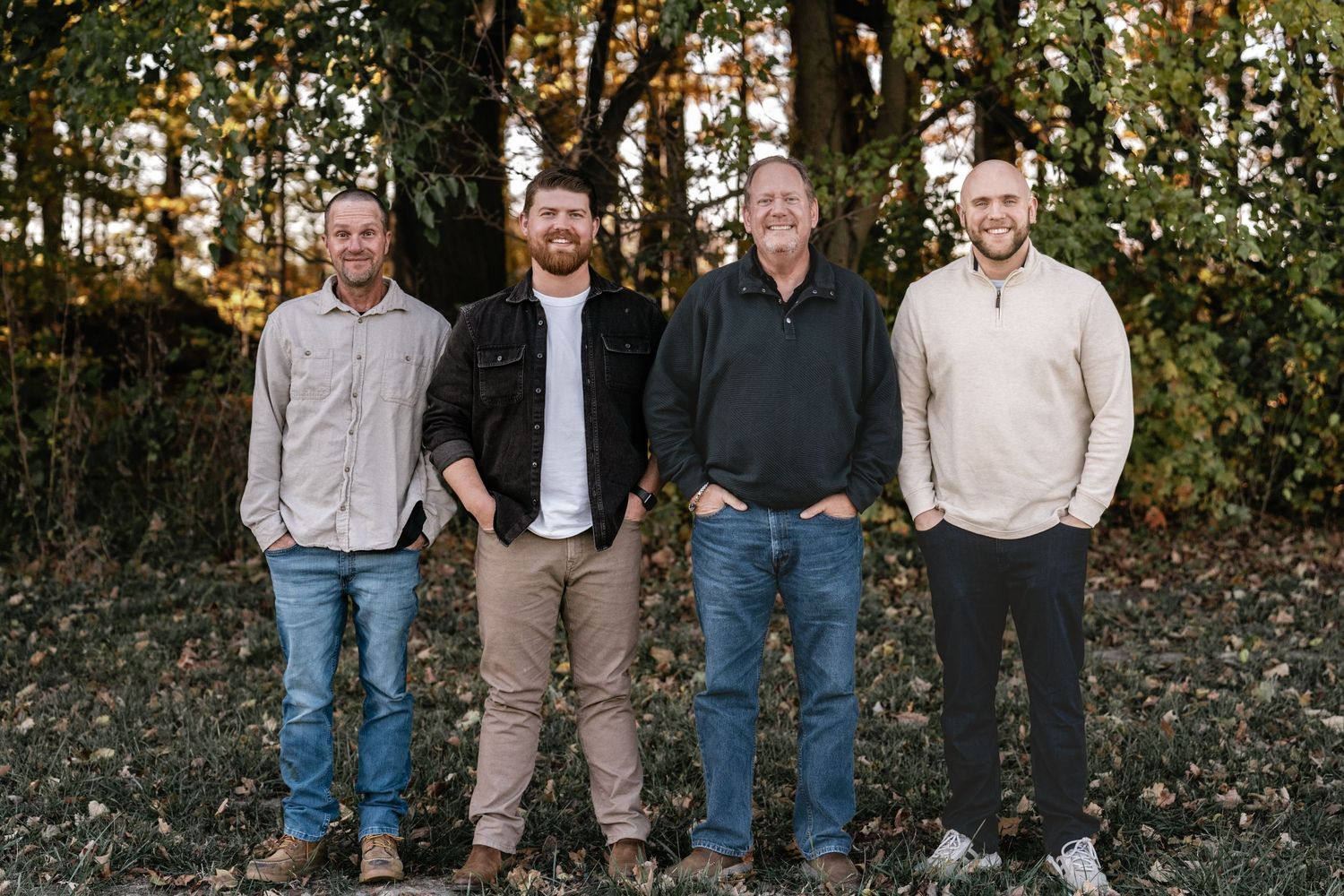 Row of people stand together for casual group photo in autumn forest.
