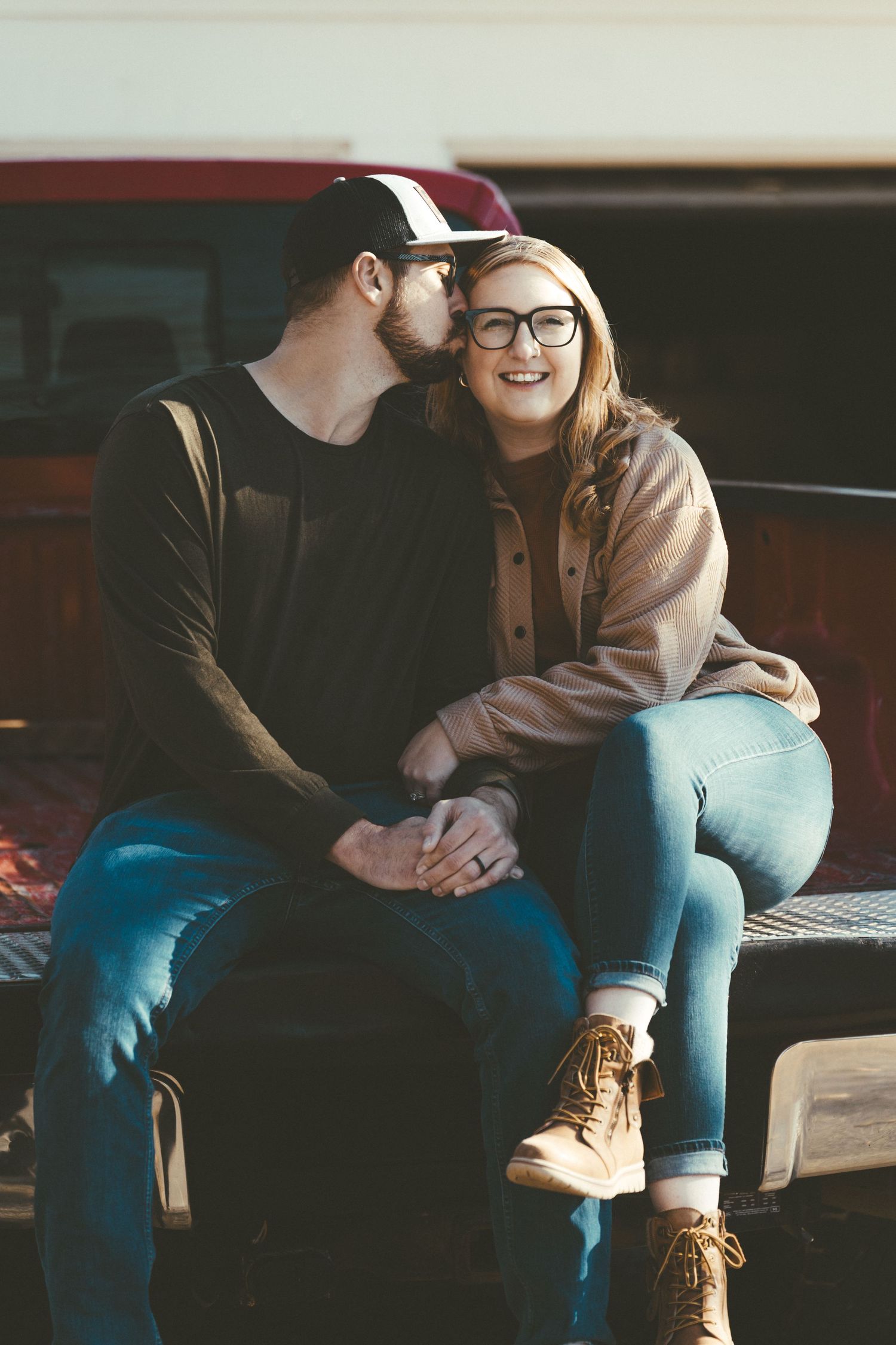Couple sitting close together on a bench sharing an intimate moment in casual attire.