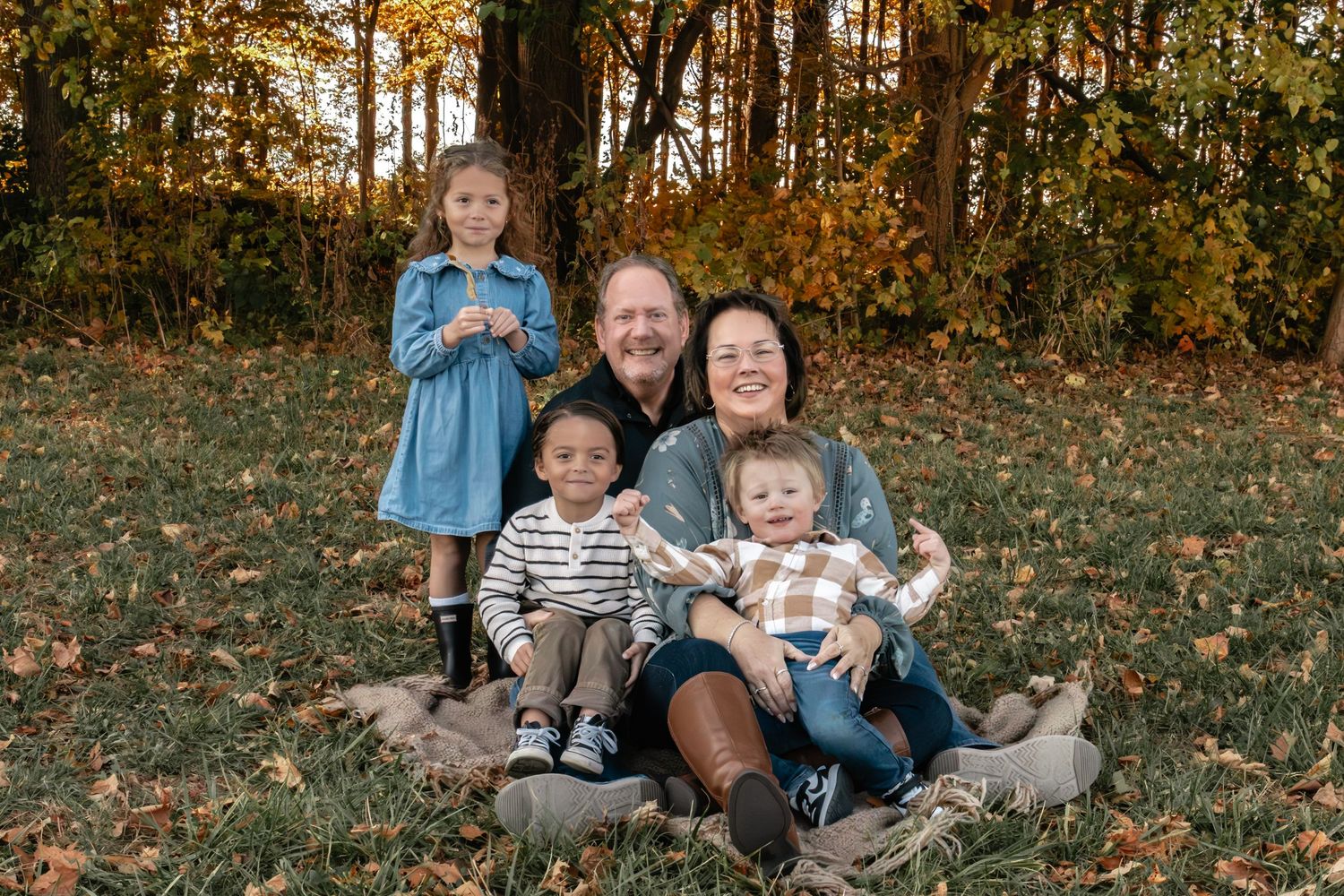 Group poses for casual outdoor family photos among autumn foliage.