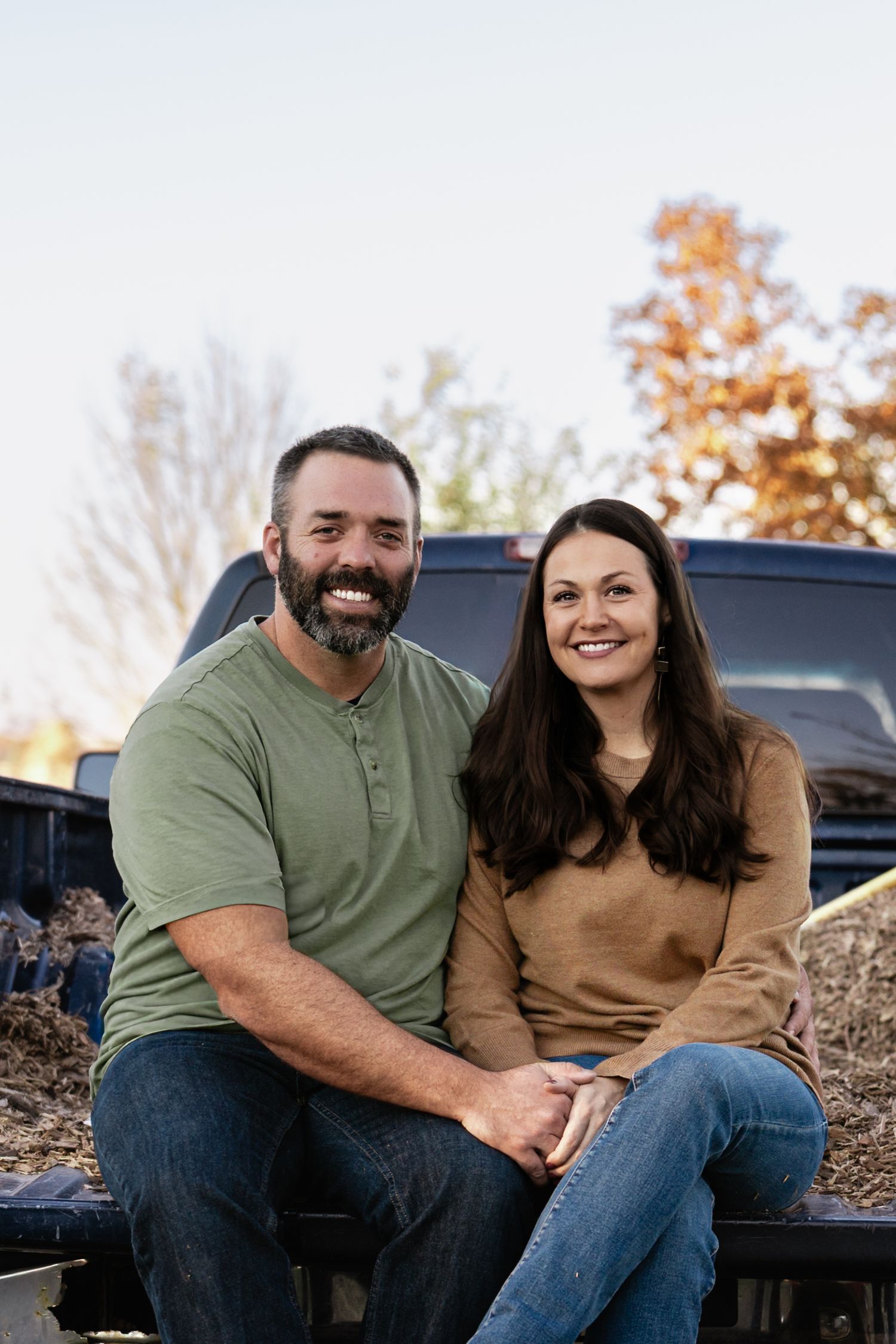 Couple sharing a relaxed moment while sitting in the bed of a pickup truck.