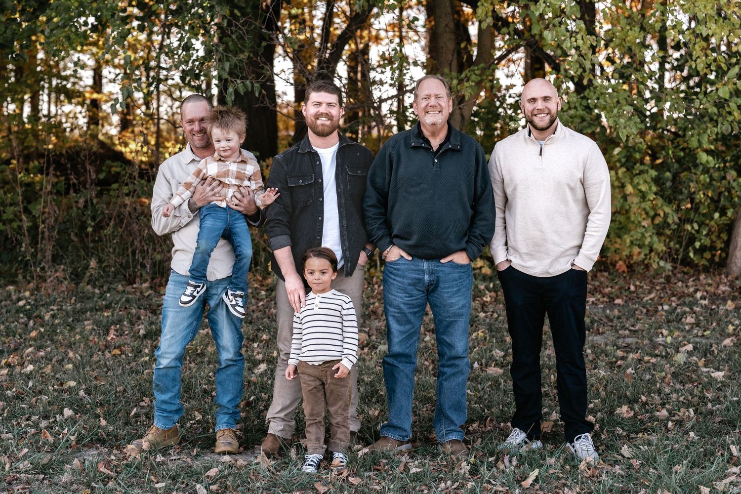 Family members sitting together on a fallen tree trunk during an autumn photo session.