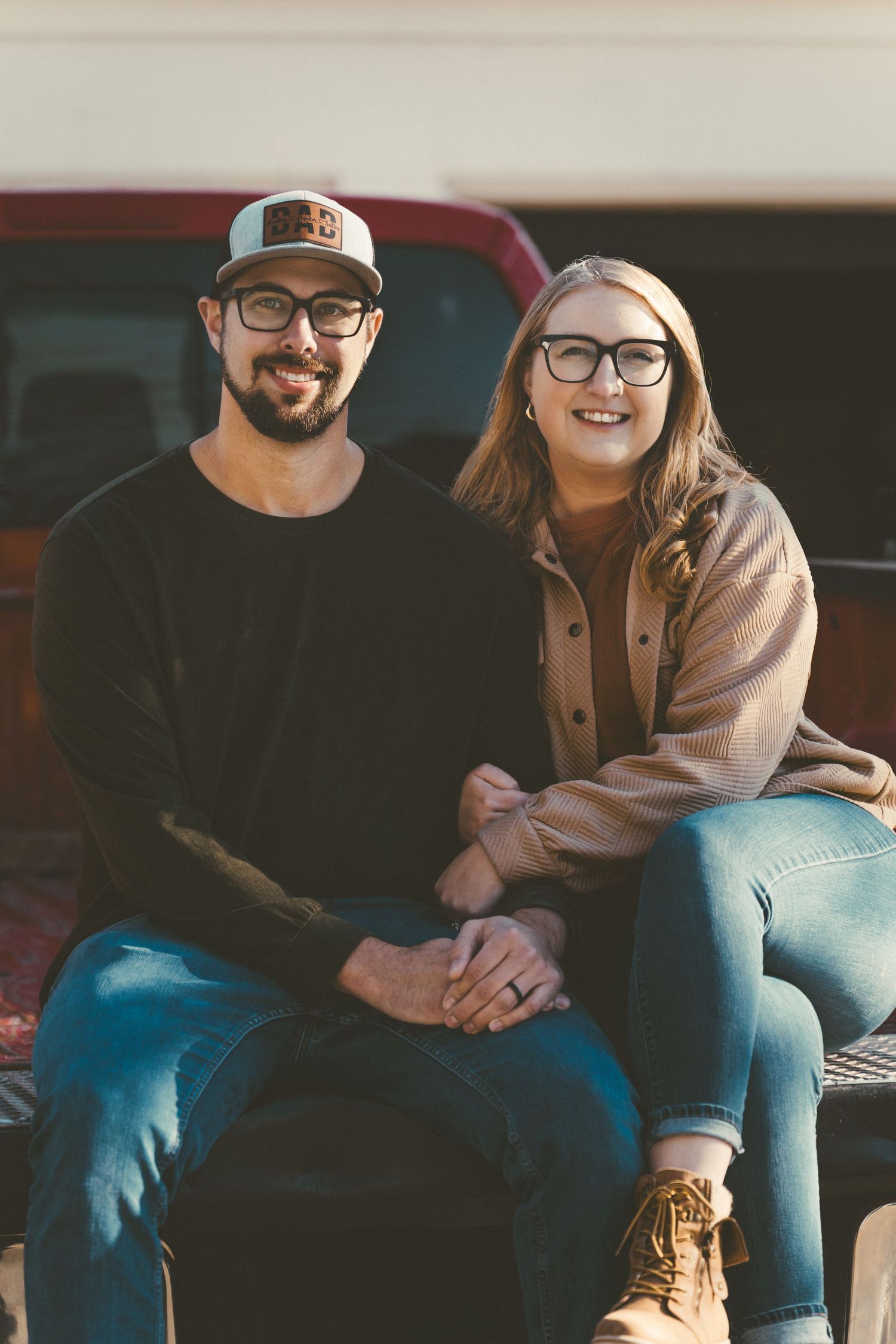 Couple in casual winter wear sitting together and smiling on a wooden bench.