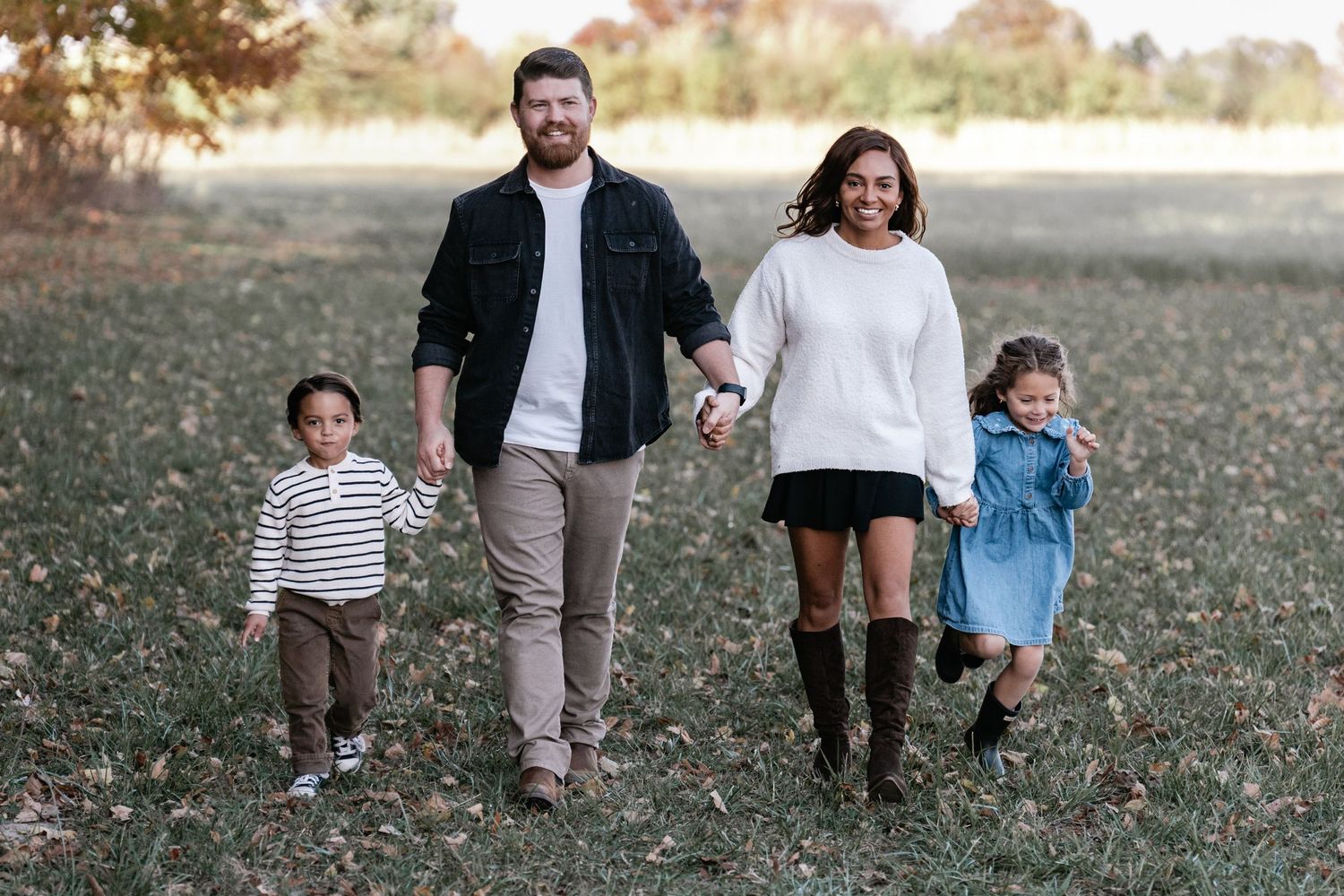 Extended family walking together through a grassy field during golden hour.