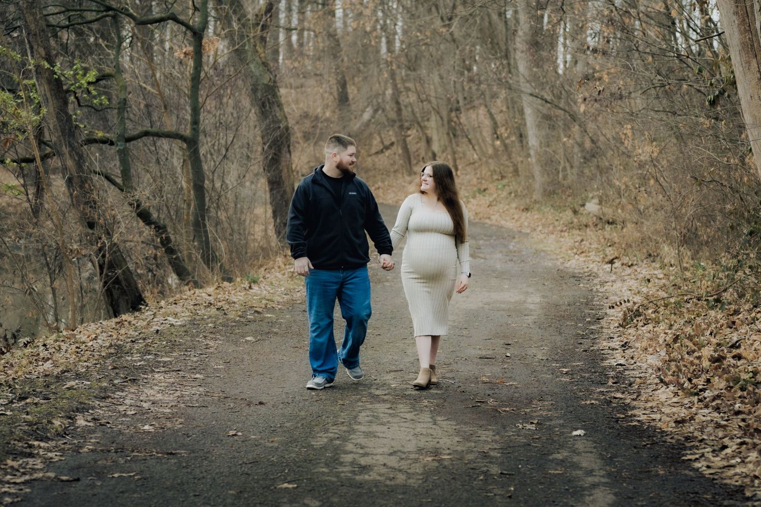 Couple walking together on a wooded trail during autumn.