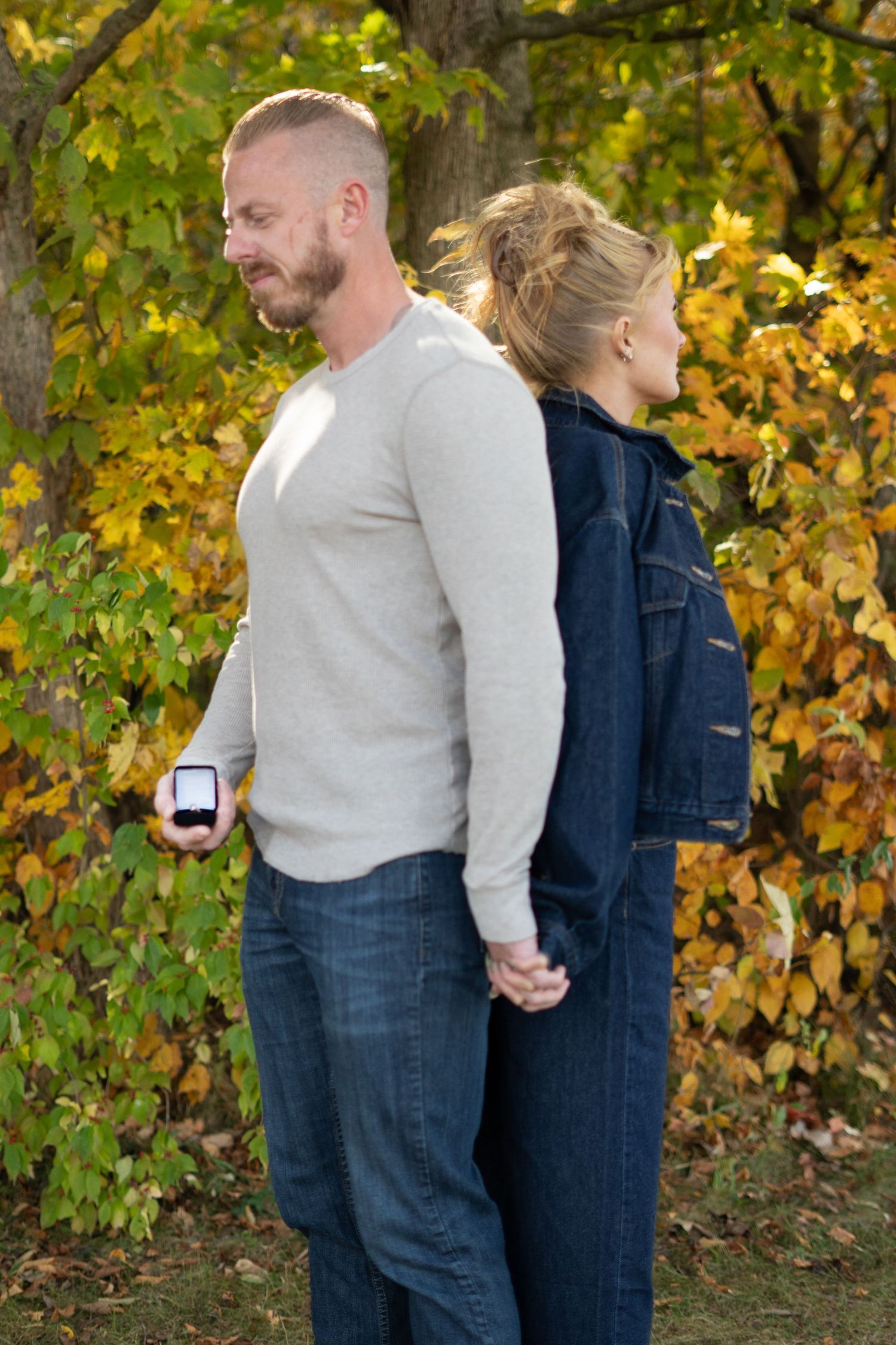 Couple in denim and casual wear sharing tender moments against autumn trees.