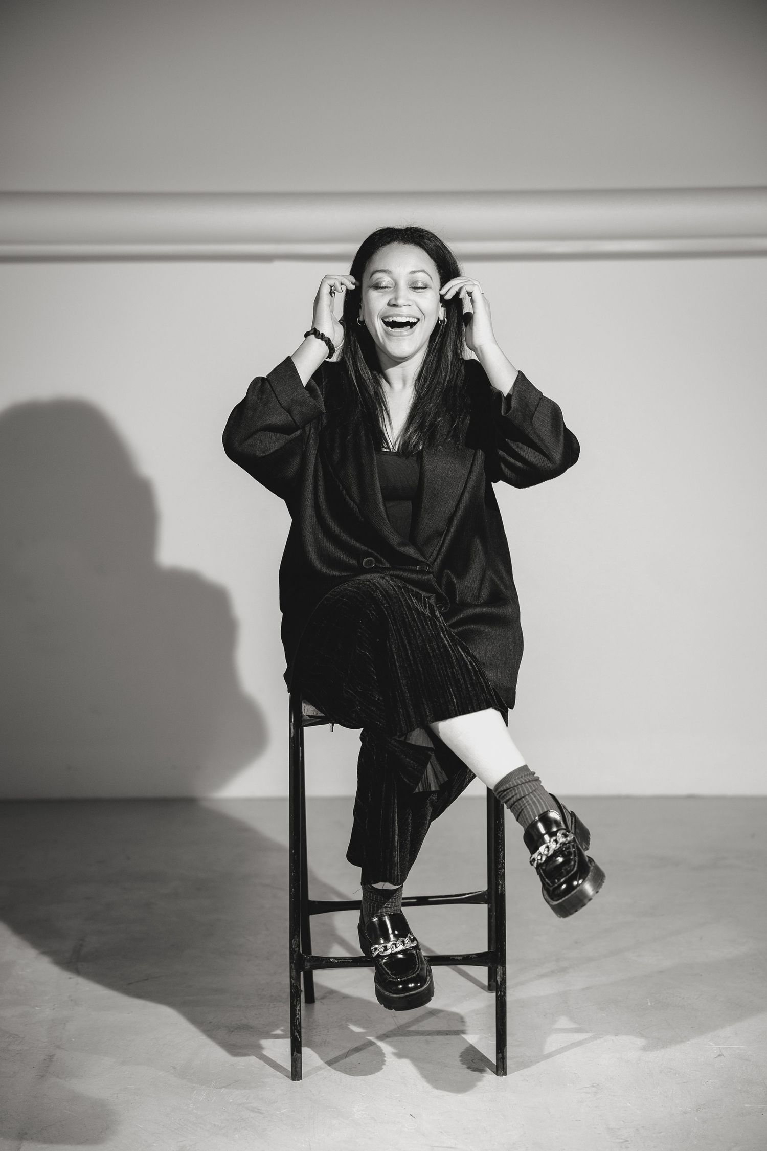 Black and white portrait series capturing expressive movements while seated on dark chair.